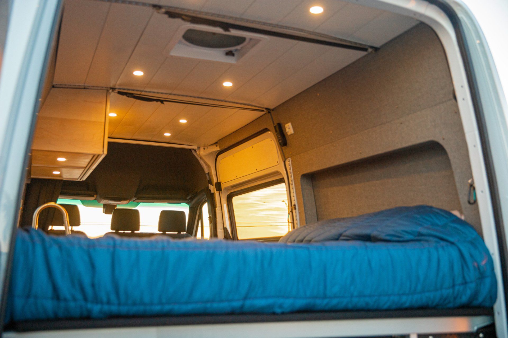 a bed in the back of a van with a blue mattress .