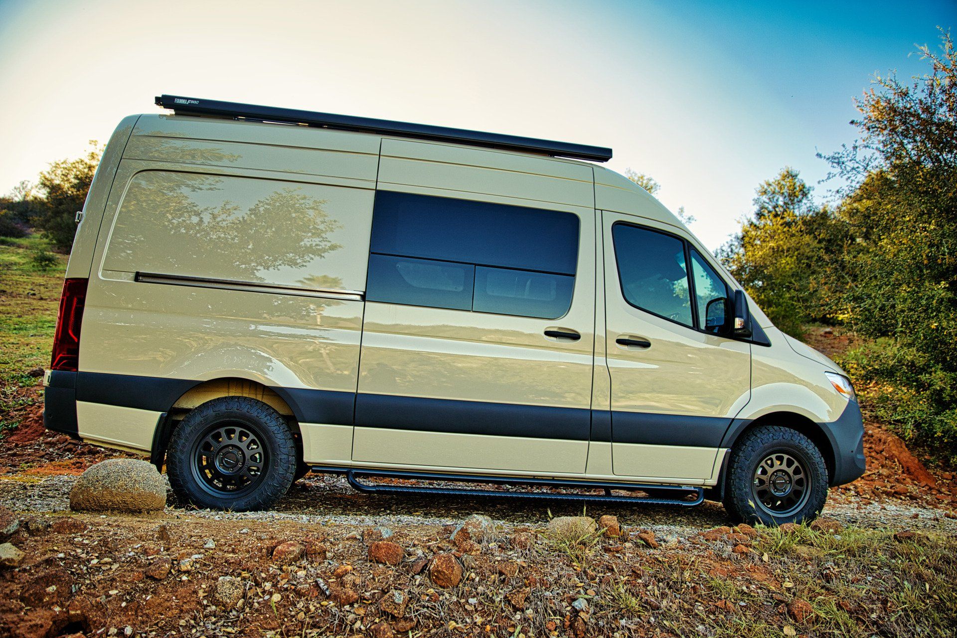 A white van is parked on top of a gravel hill.