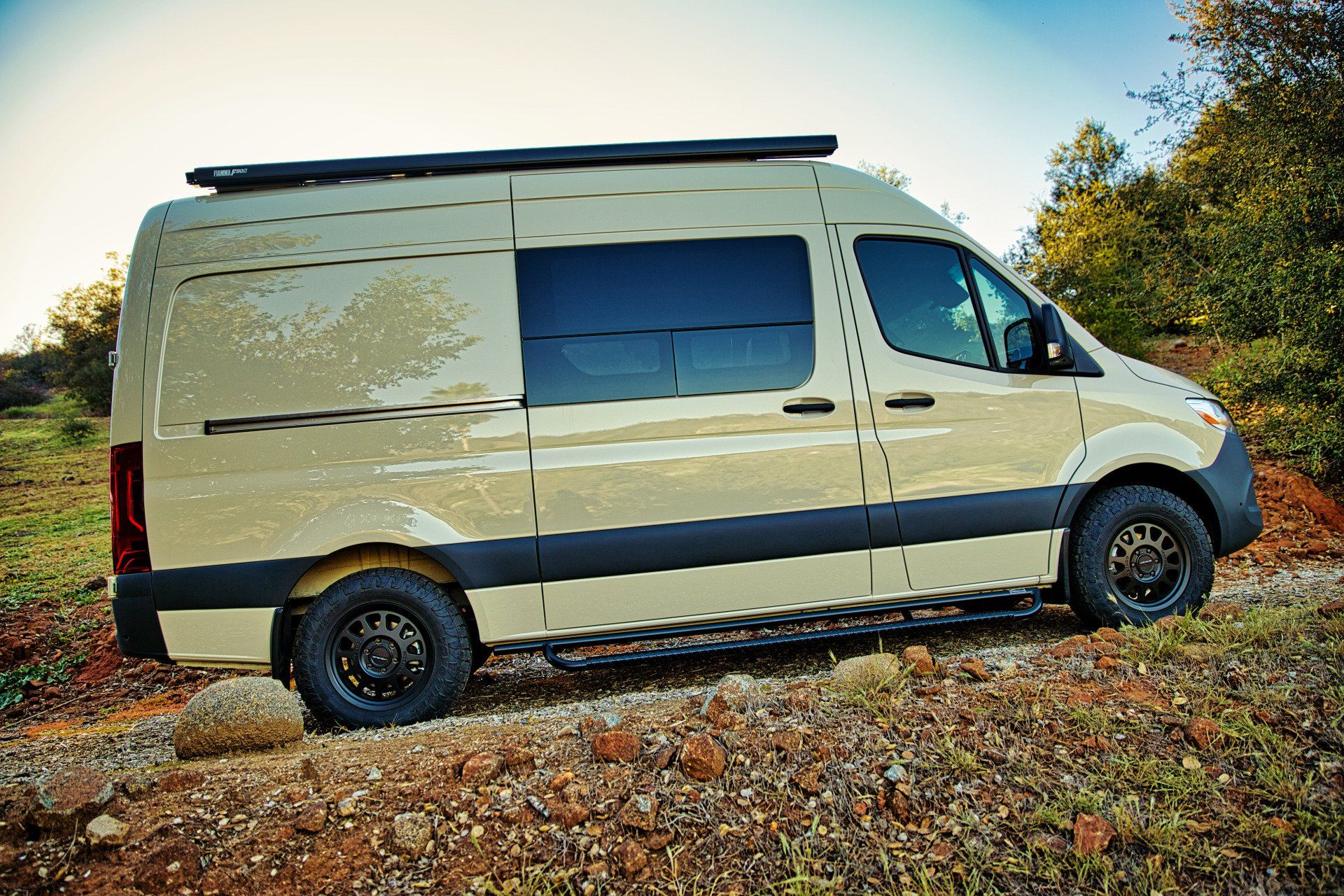 A van is parked on the side of a dirt road.