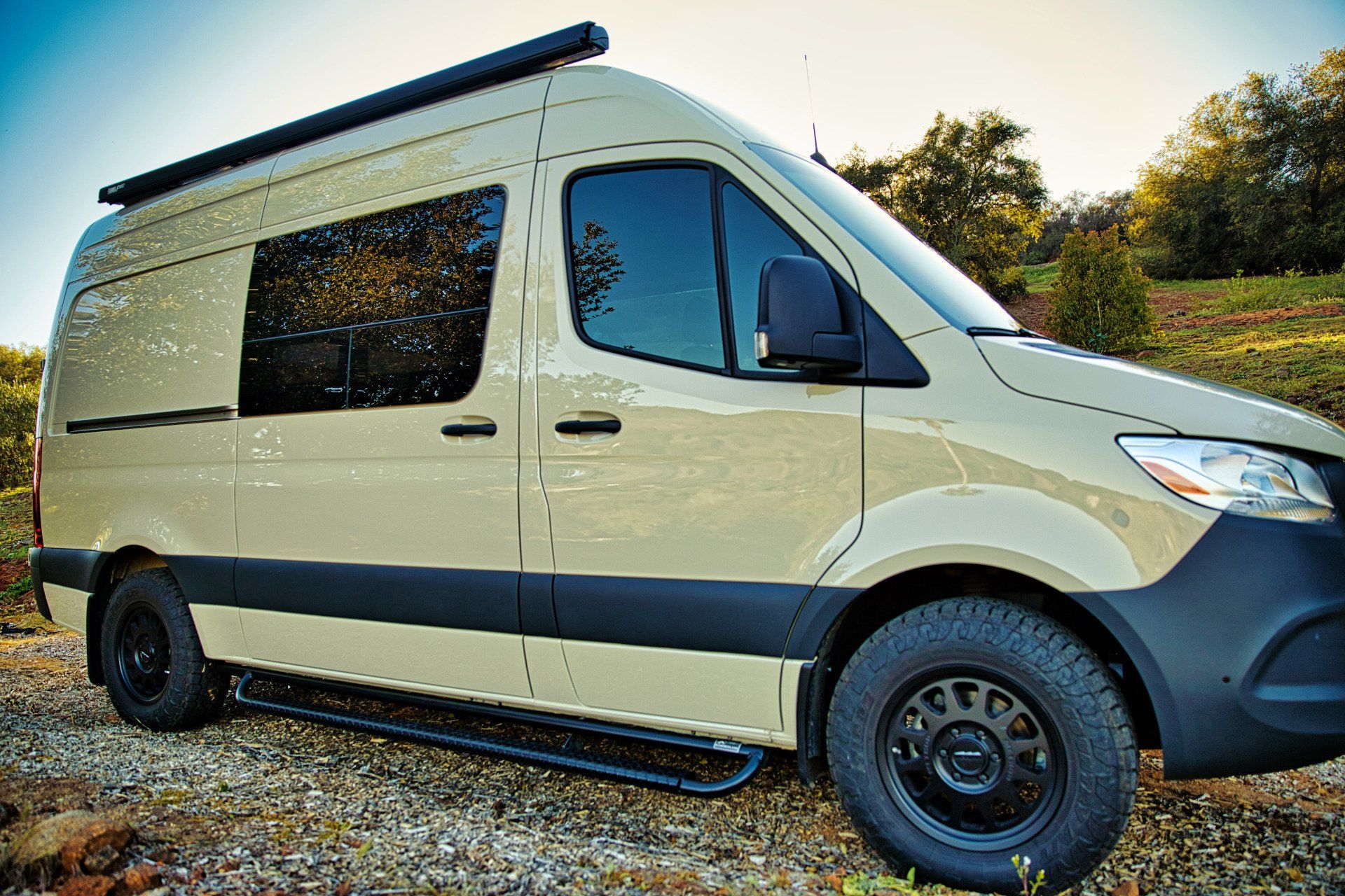 A white van is parked on a gravel road.