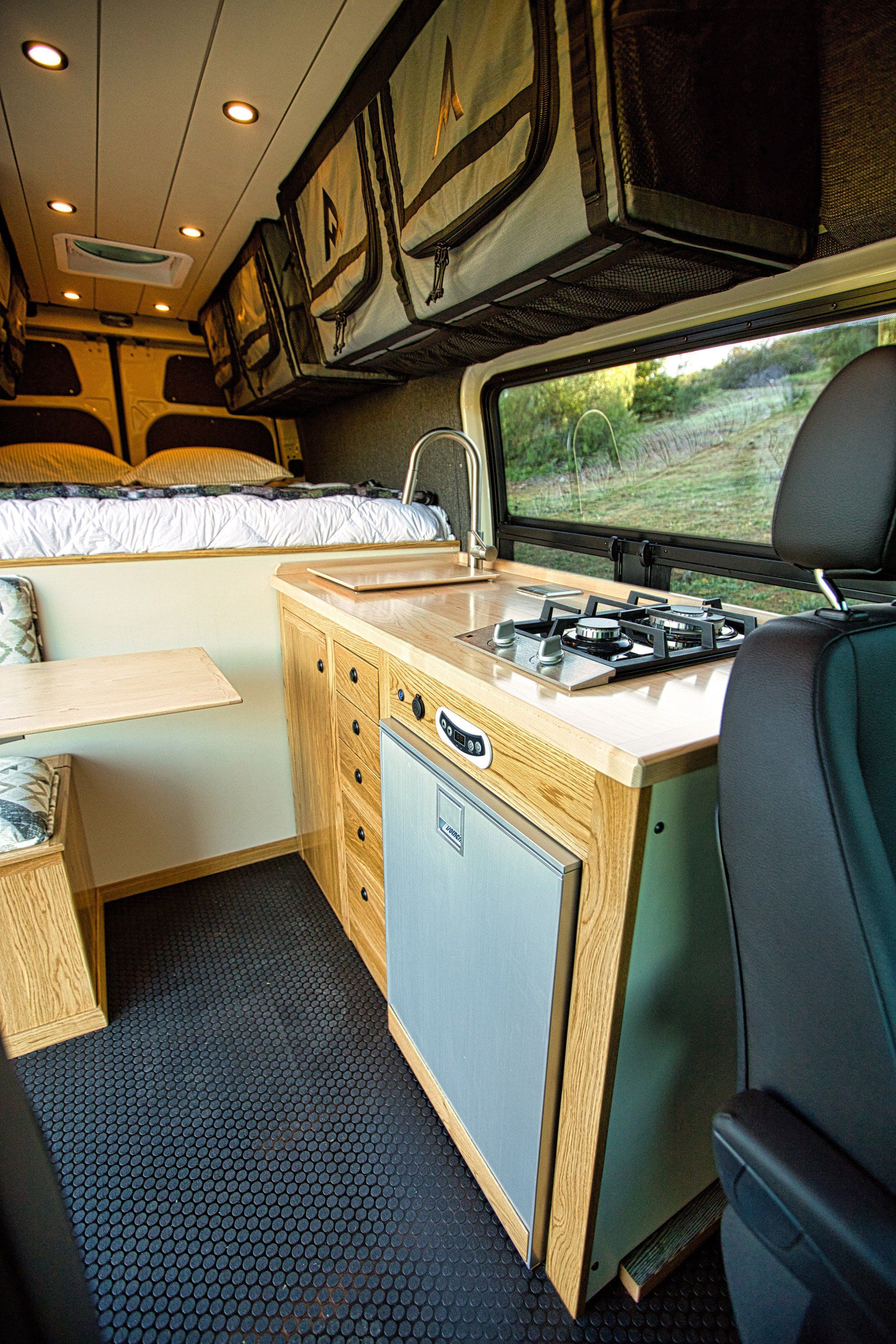 The inside of a van with a stove , sink , and table.