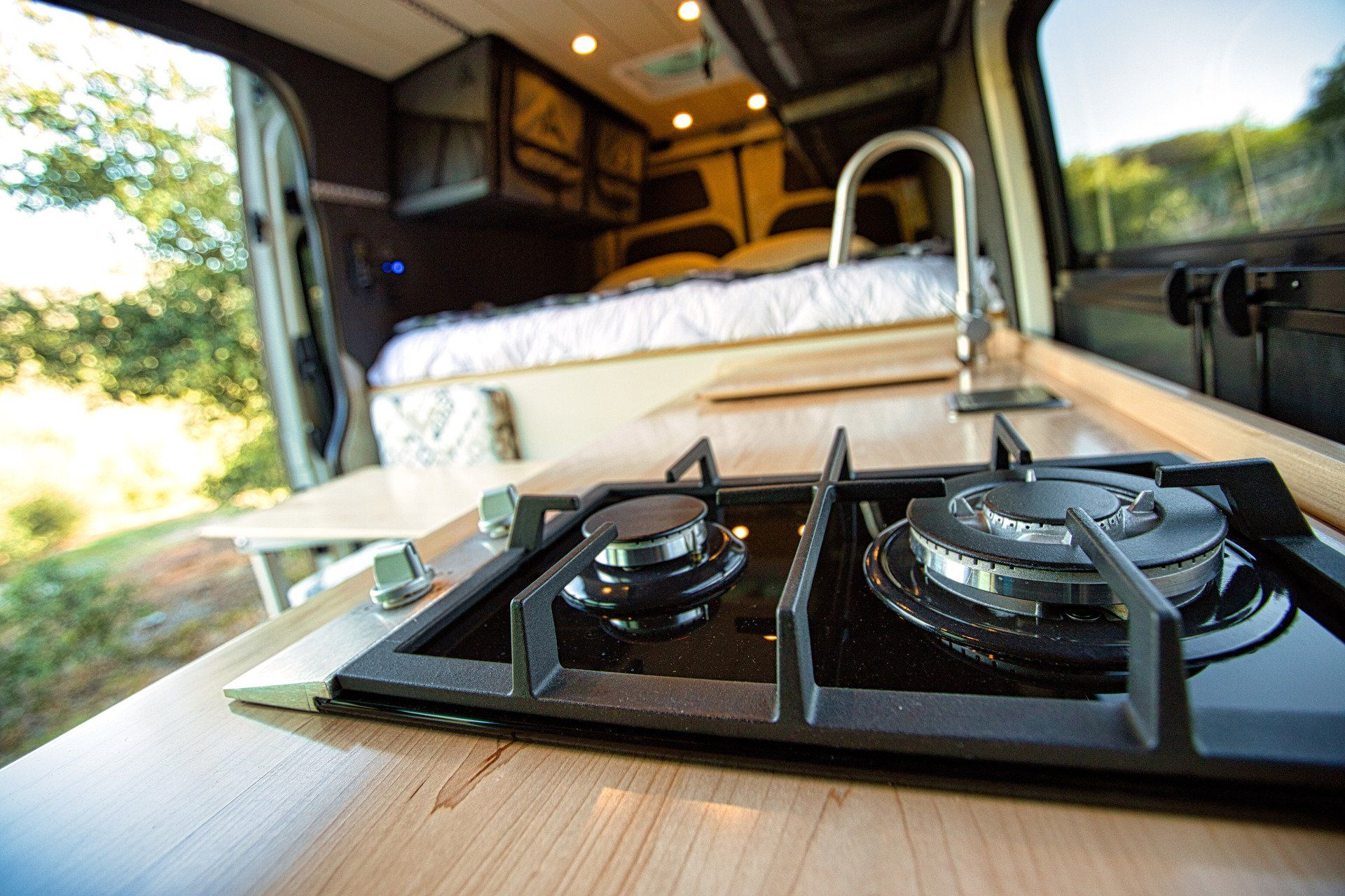 A stove top oven is sitting on a wooden counter in a van.