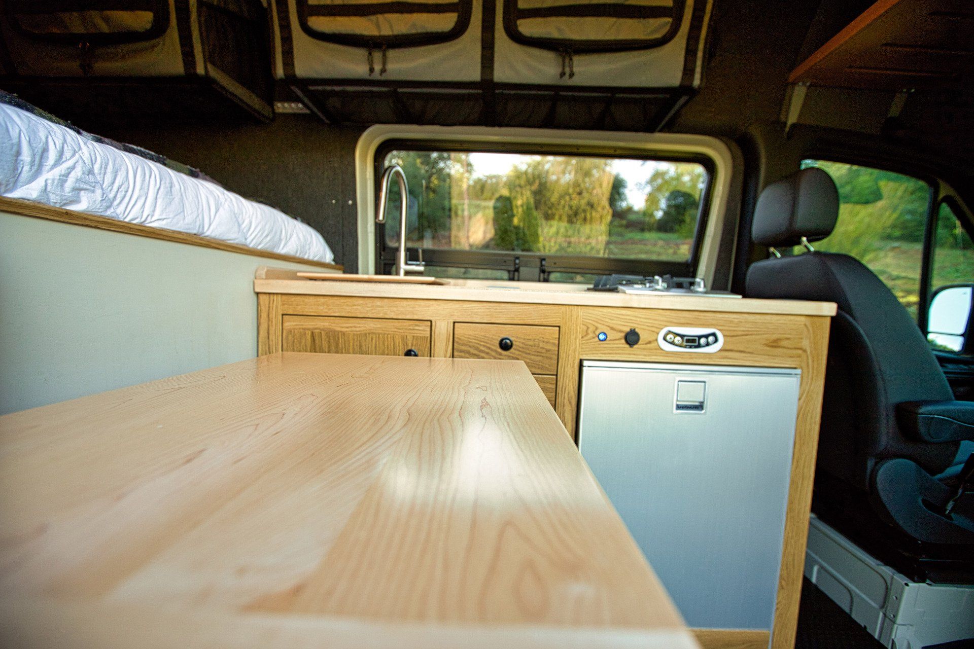 The inside of a van with a wooden table and cabinets.