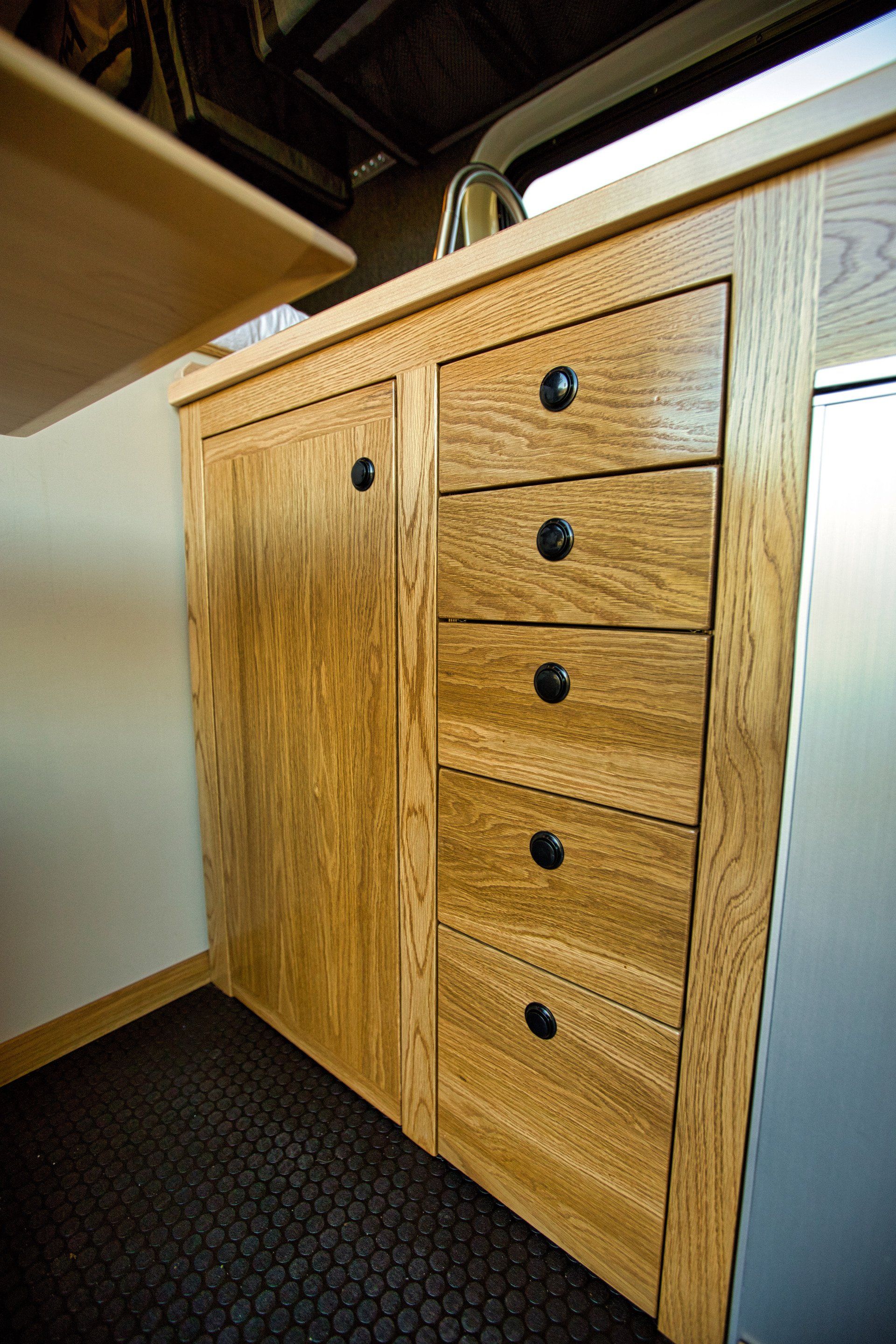 A kitchen with wooden cabinets and drawers and a stainless steel refrigerator.