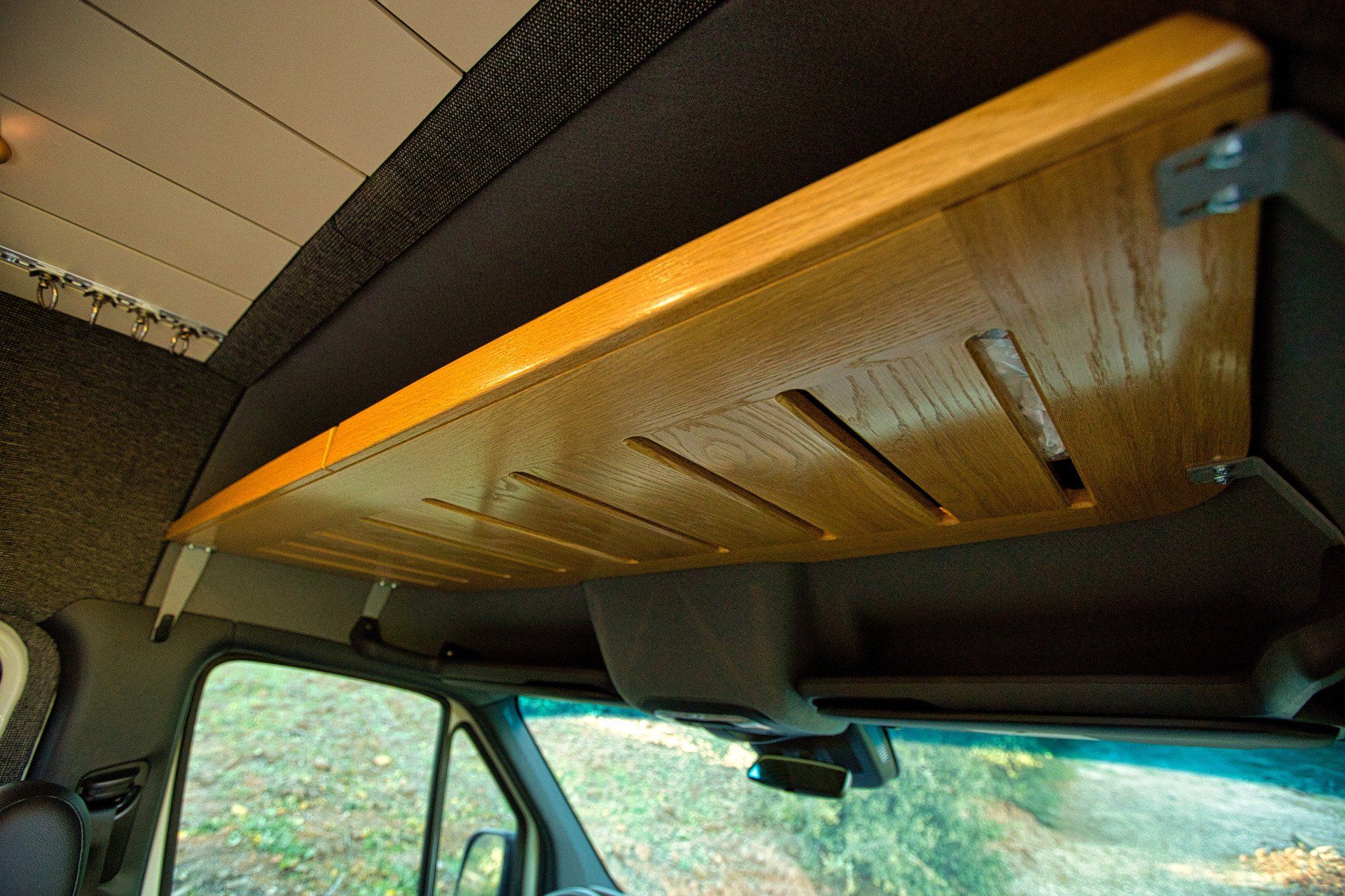 A wooden table is hanging from the ceiling of a van.