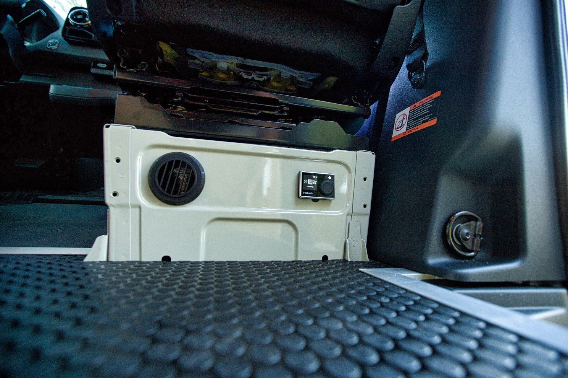 A car with a black mat on the floor and a white box under the seat.