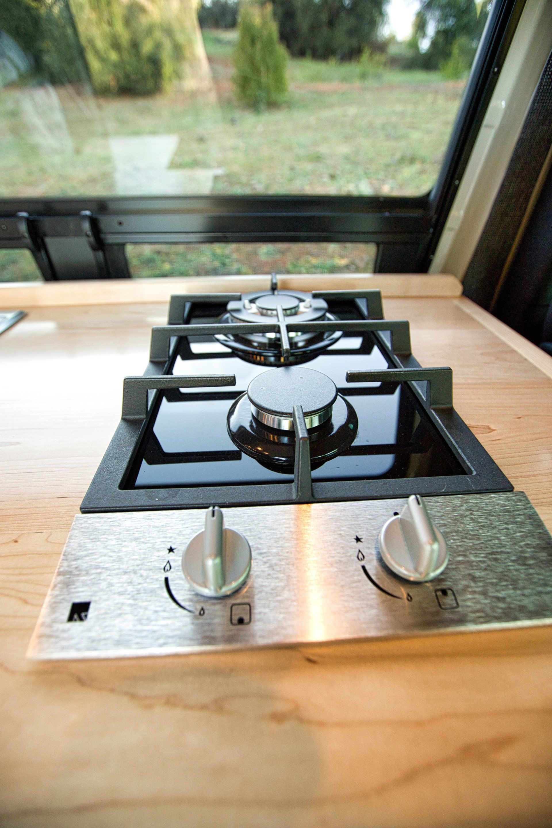 A gas stove is sitting on a wooden counter next to a window.
