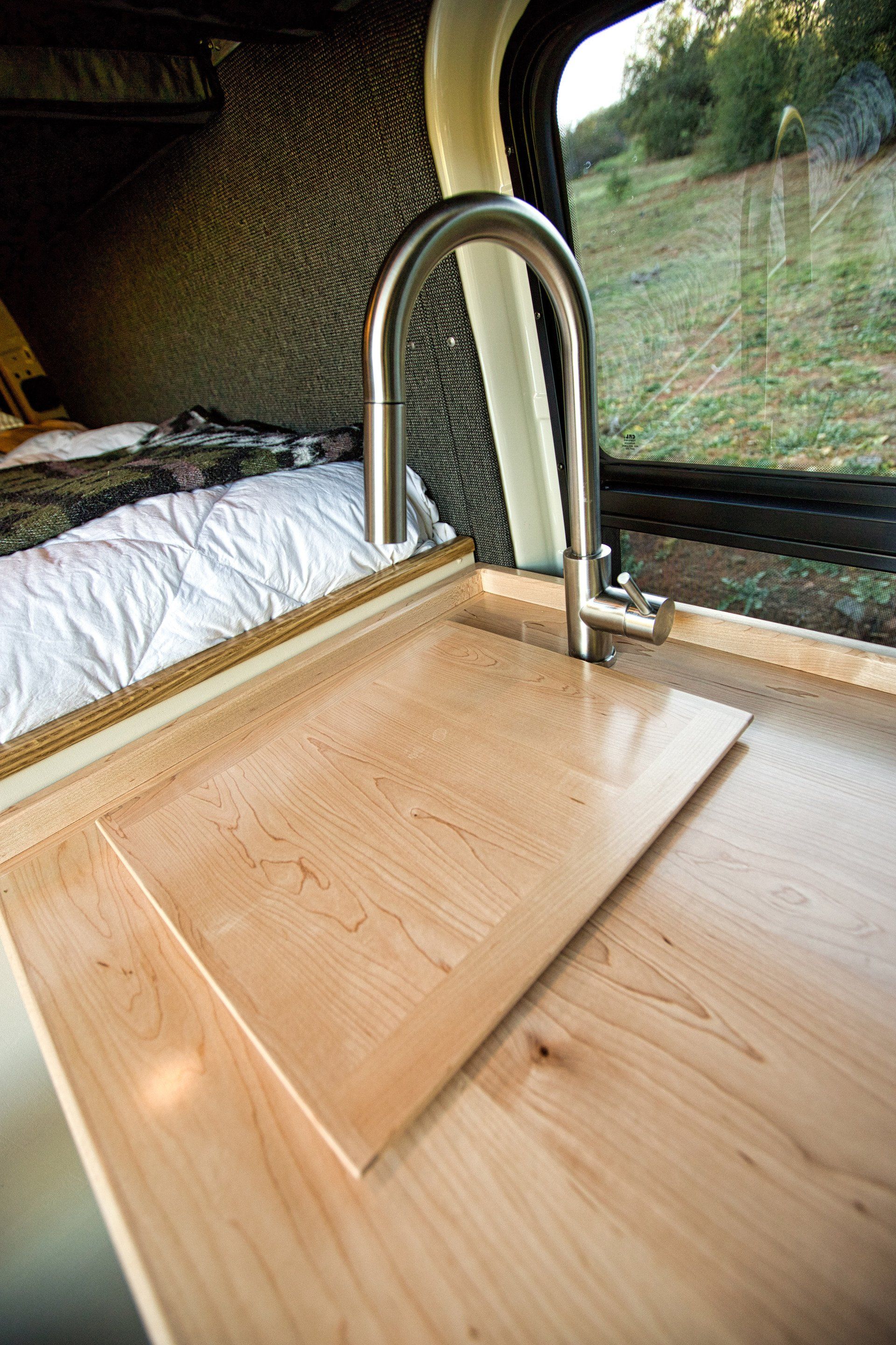 A kitchen sink with a wooden counter top and a stainless steel faucet.