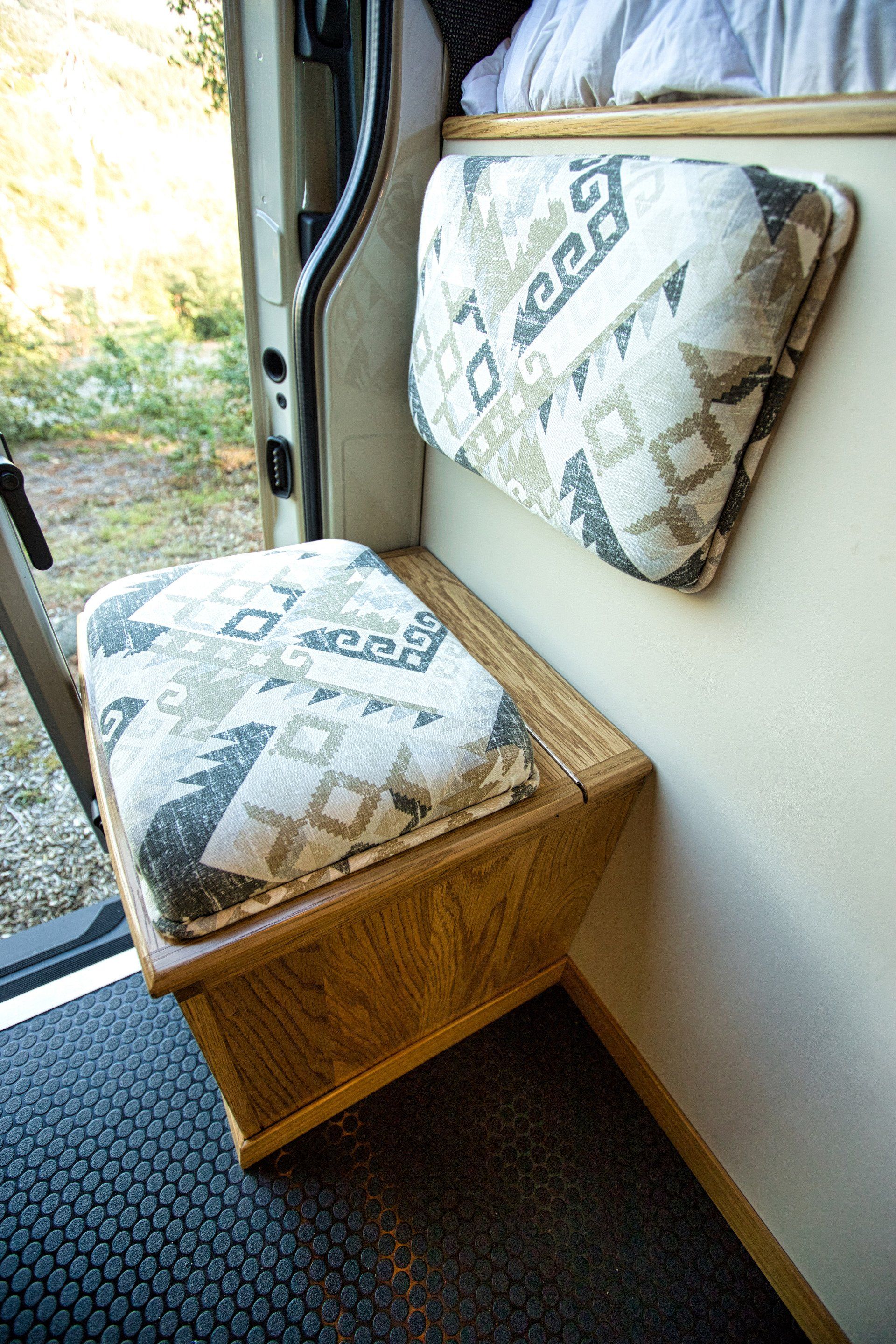 A wooden bench with two pillows on it in a van.