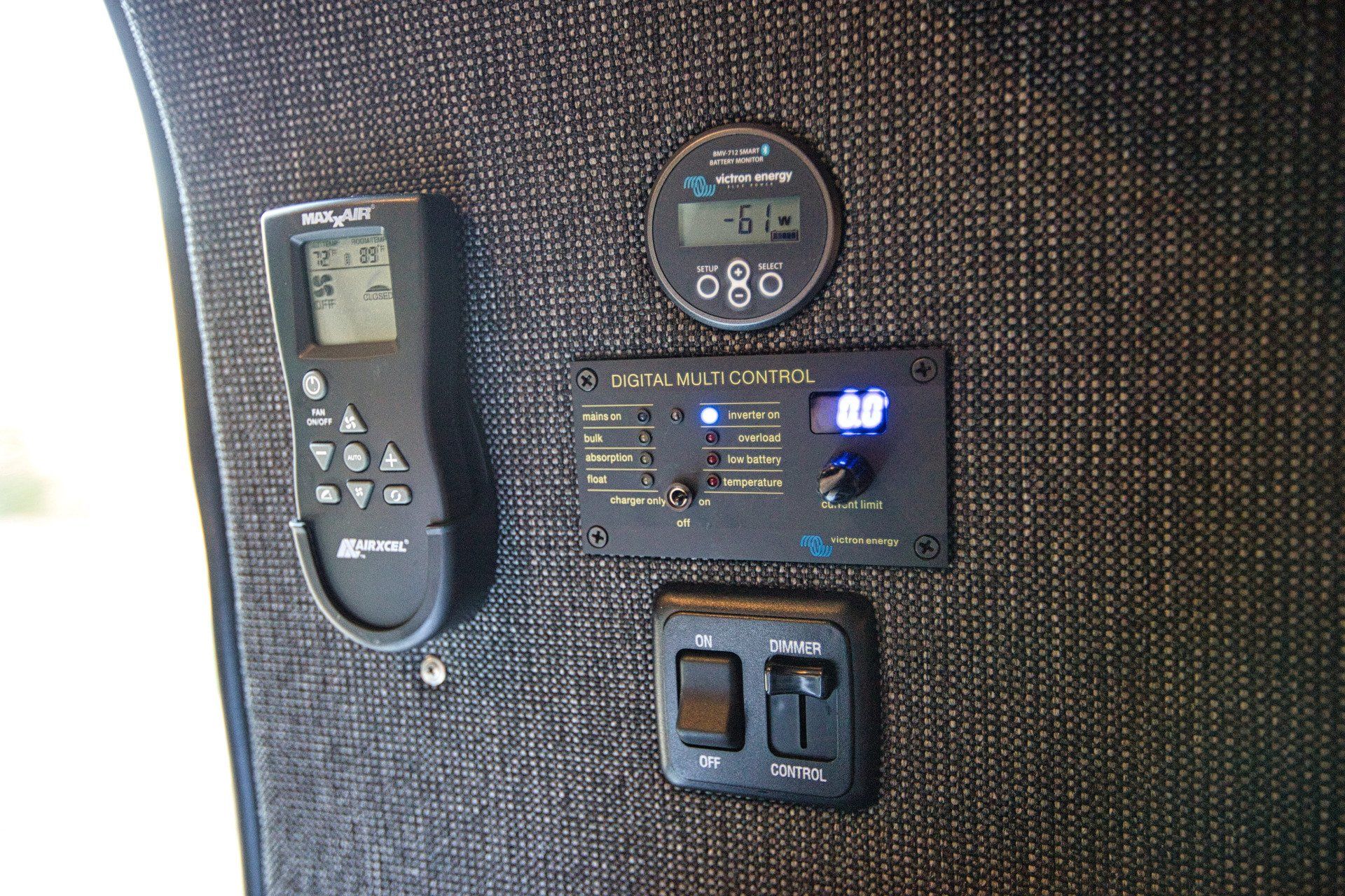 A remote control is sitting on a wall next to a switch.