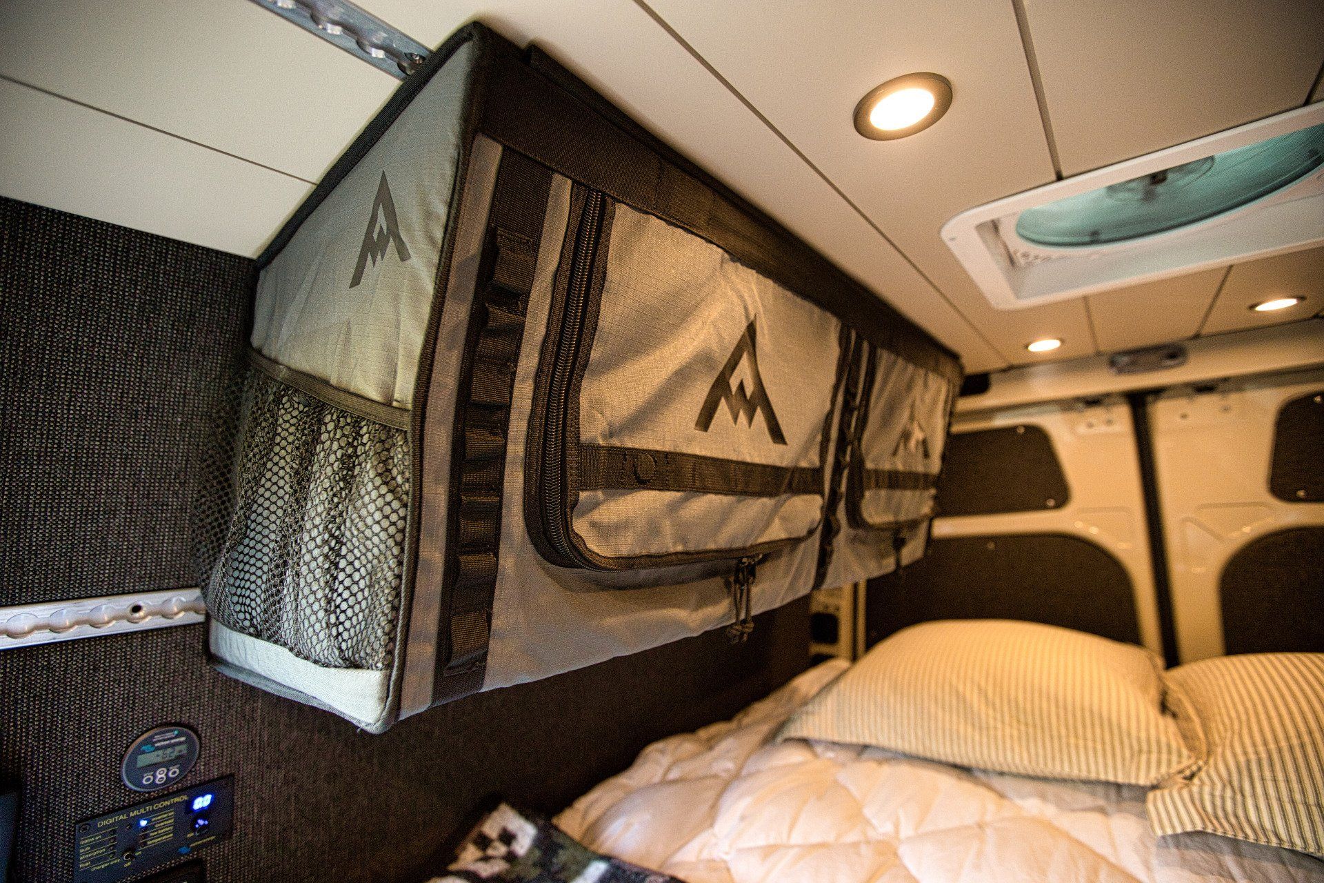 The inside of a van with a bed and a ceiling fan.