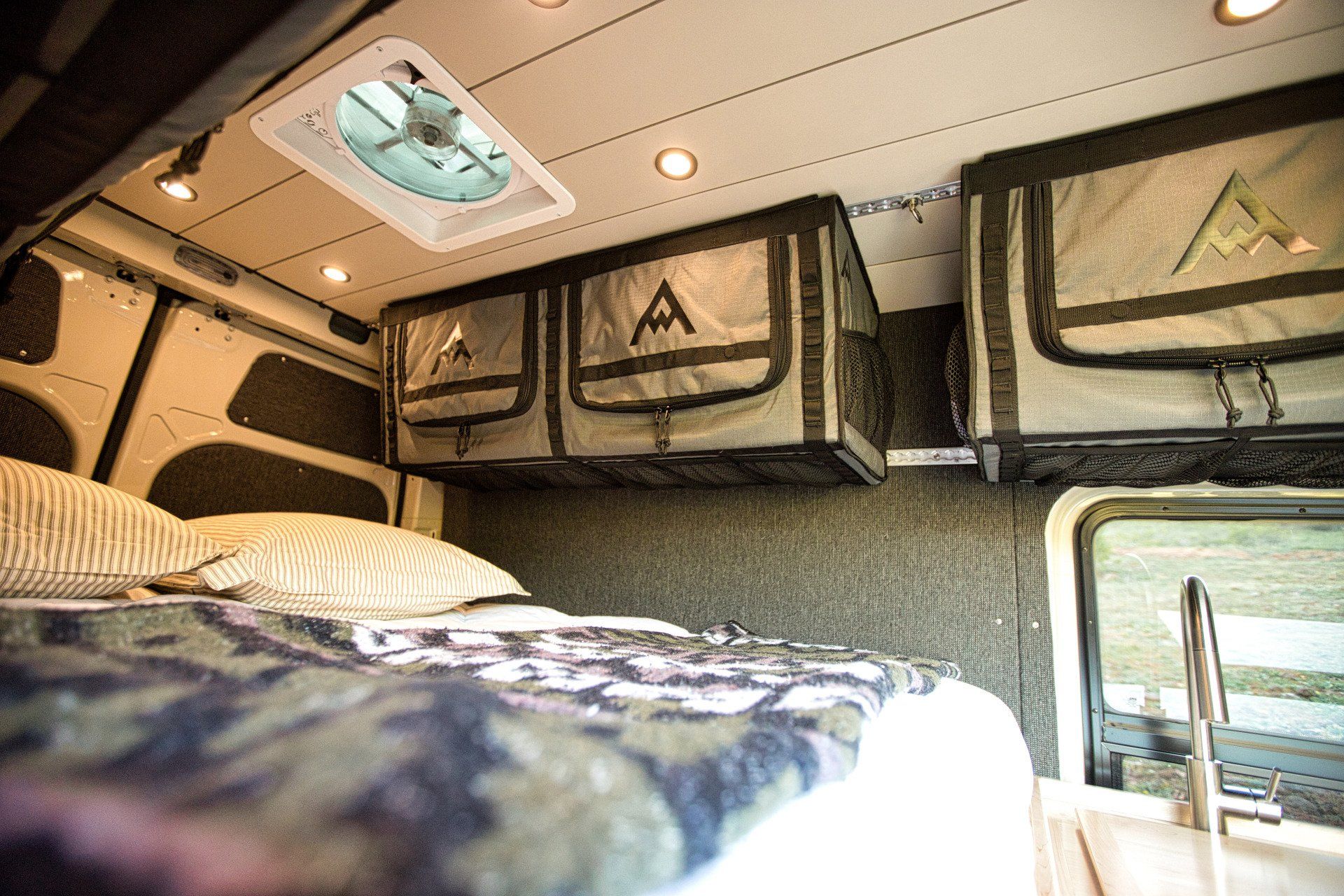 A camper van with a bed and a fan on the ceiling.
