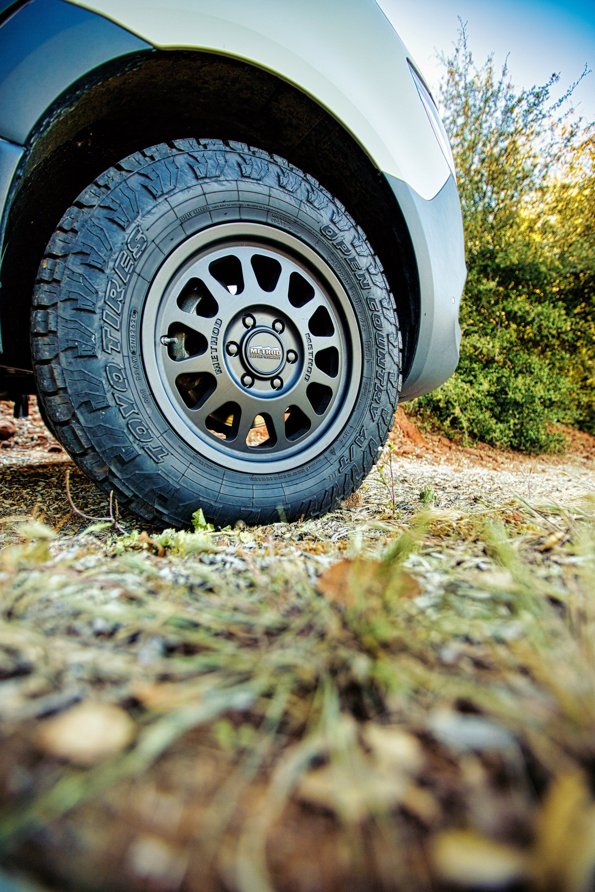 A close up of a tire on a car on a dirt road.