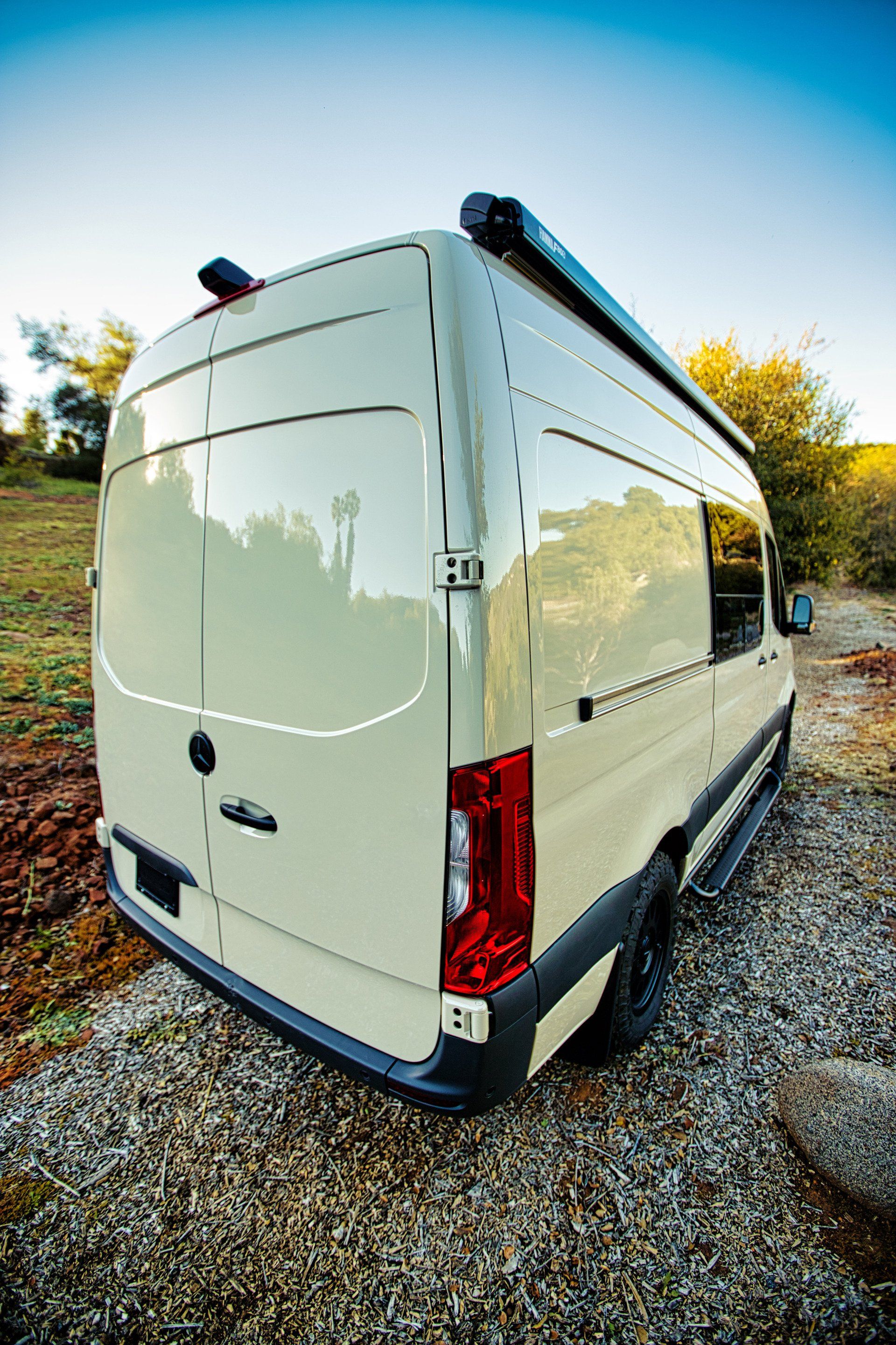 A white van is parked on a gravel road.