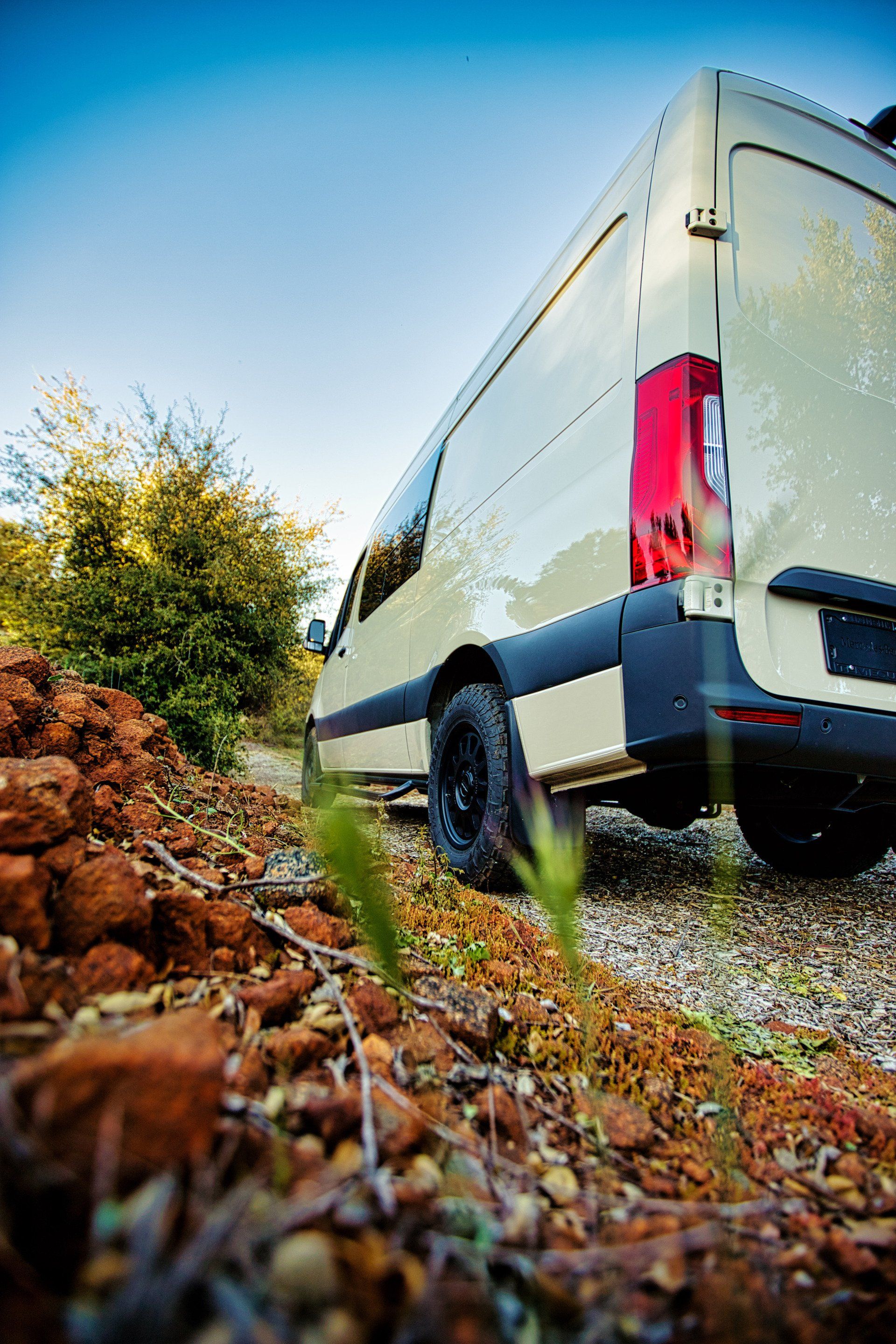 A white van is parked on a gravel road.