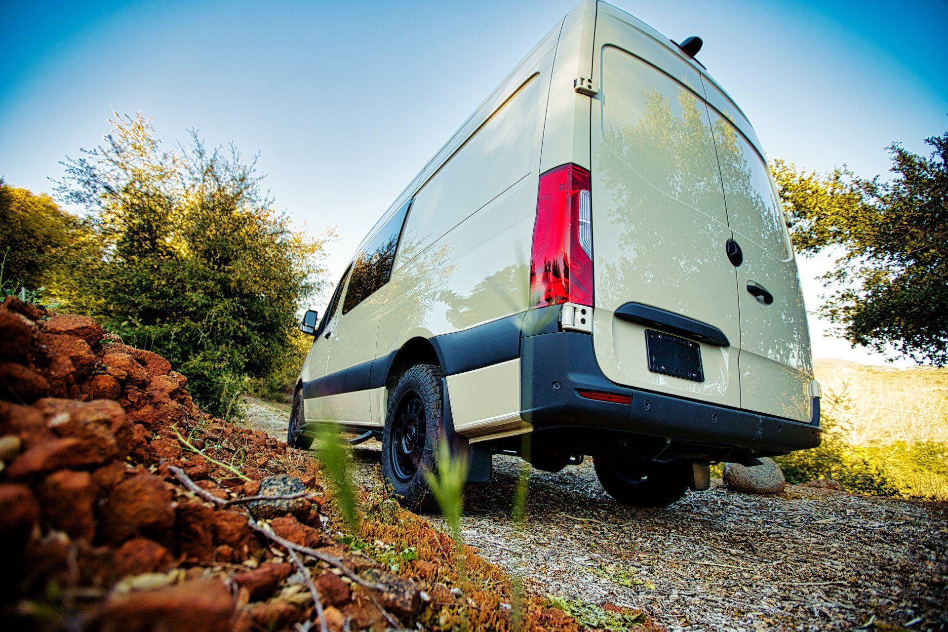 A white van is parked on a gravel road.