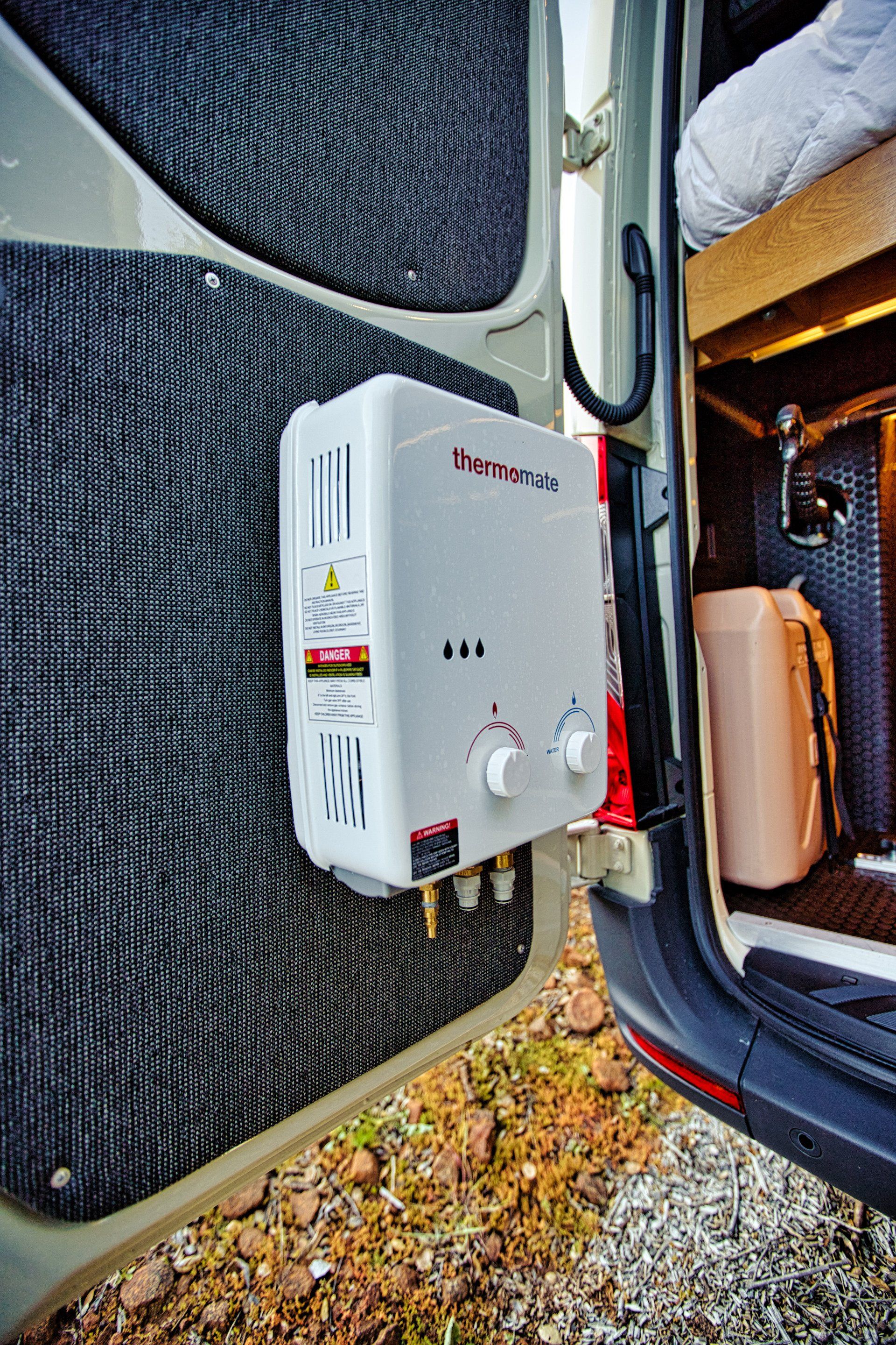 A portable water heater is attached to the back door of a van.
