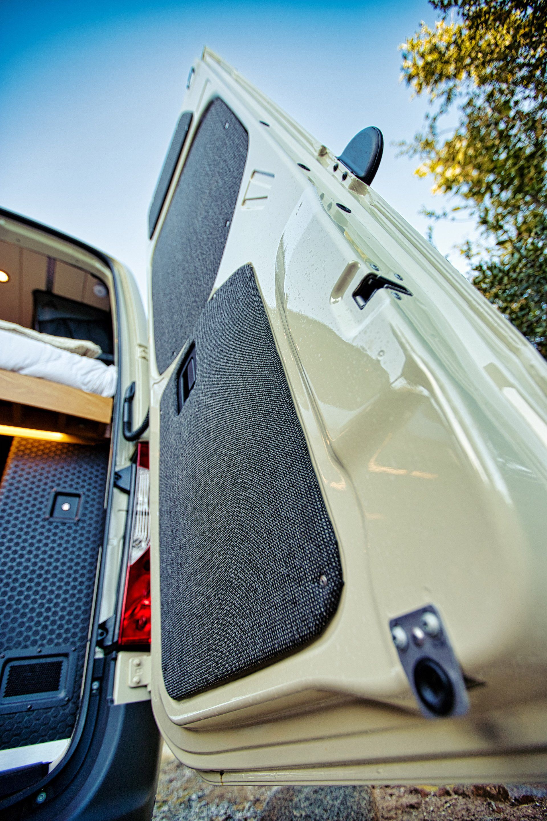 A van with the door open and a bed in the back.