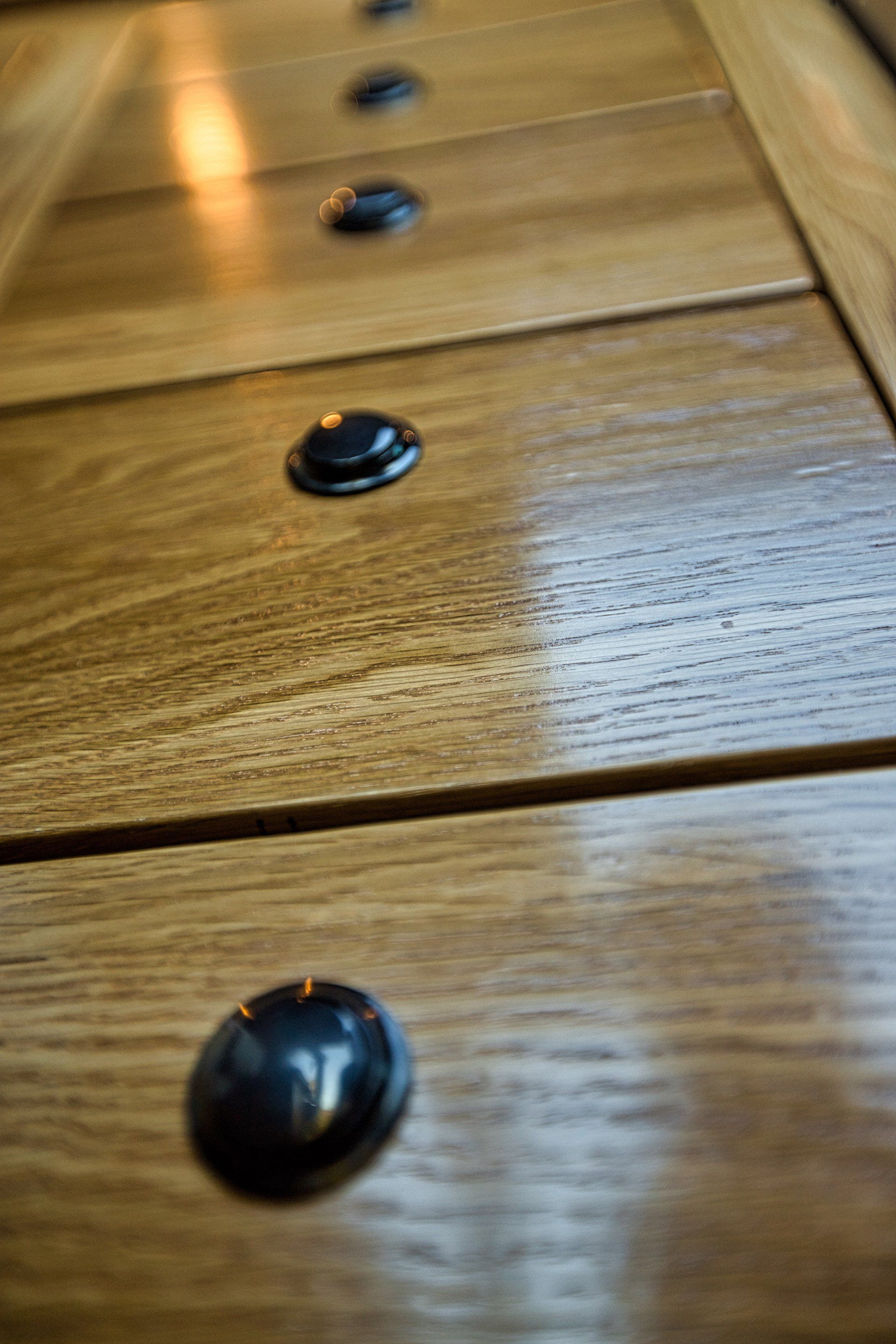 A close up of a row of wooden drawers with black knobs.