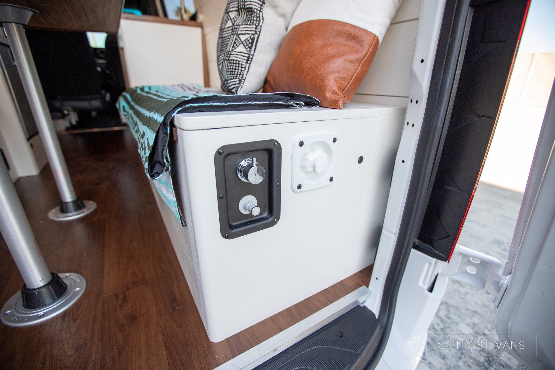 There is a couch in the back of a van with a blanket on it.