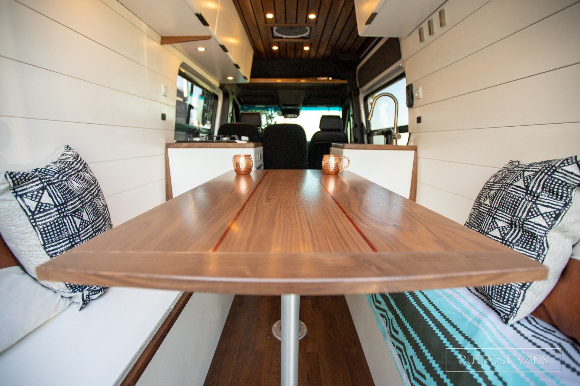 The inside of a van with a wooden table and benches.
