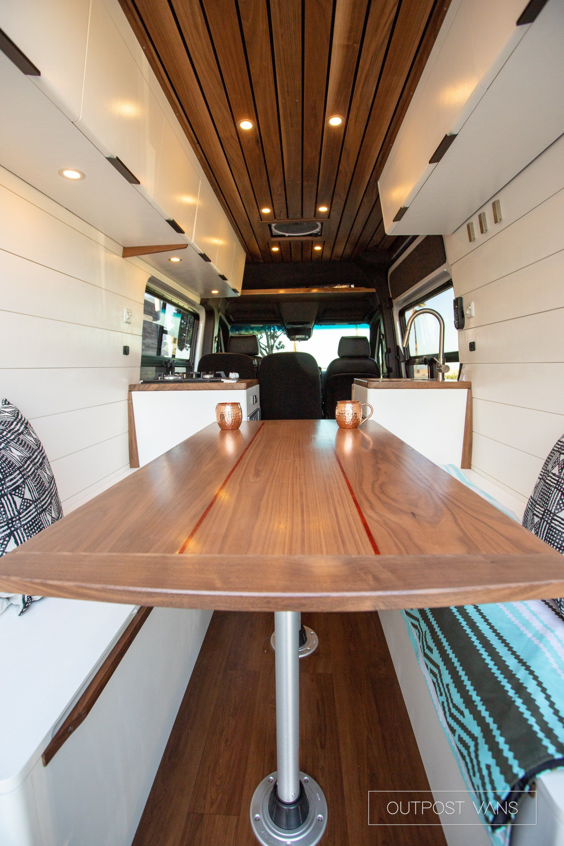 The inside of a van with a wooden table and benches.