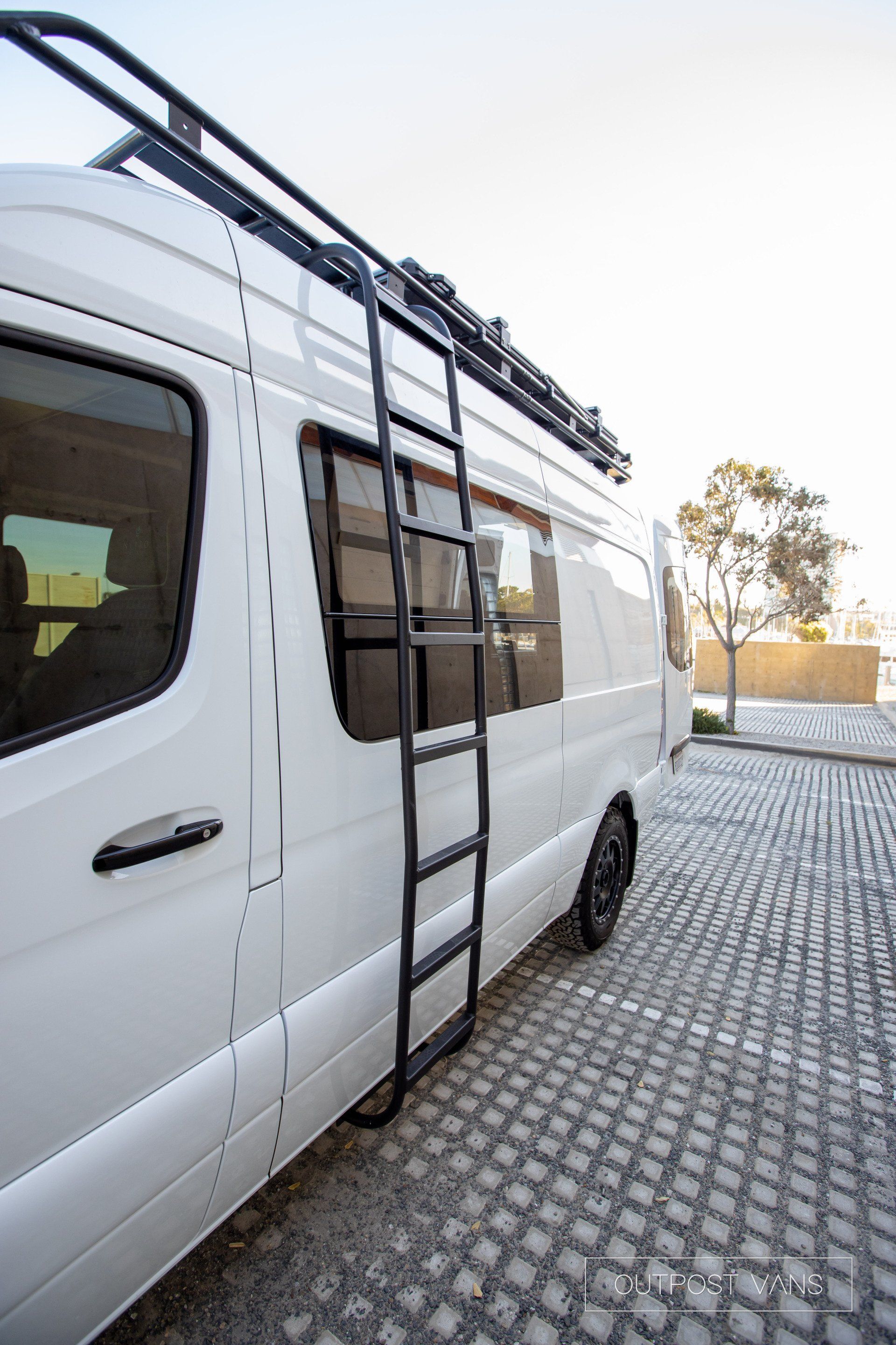 A white van with a ladder attached to the side of it.