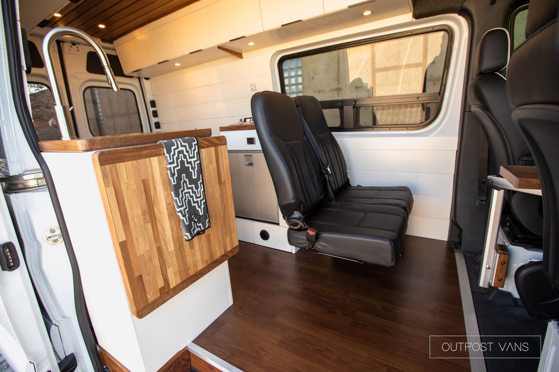 The inside of a camper van with a kitchen and two seats.
