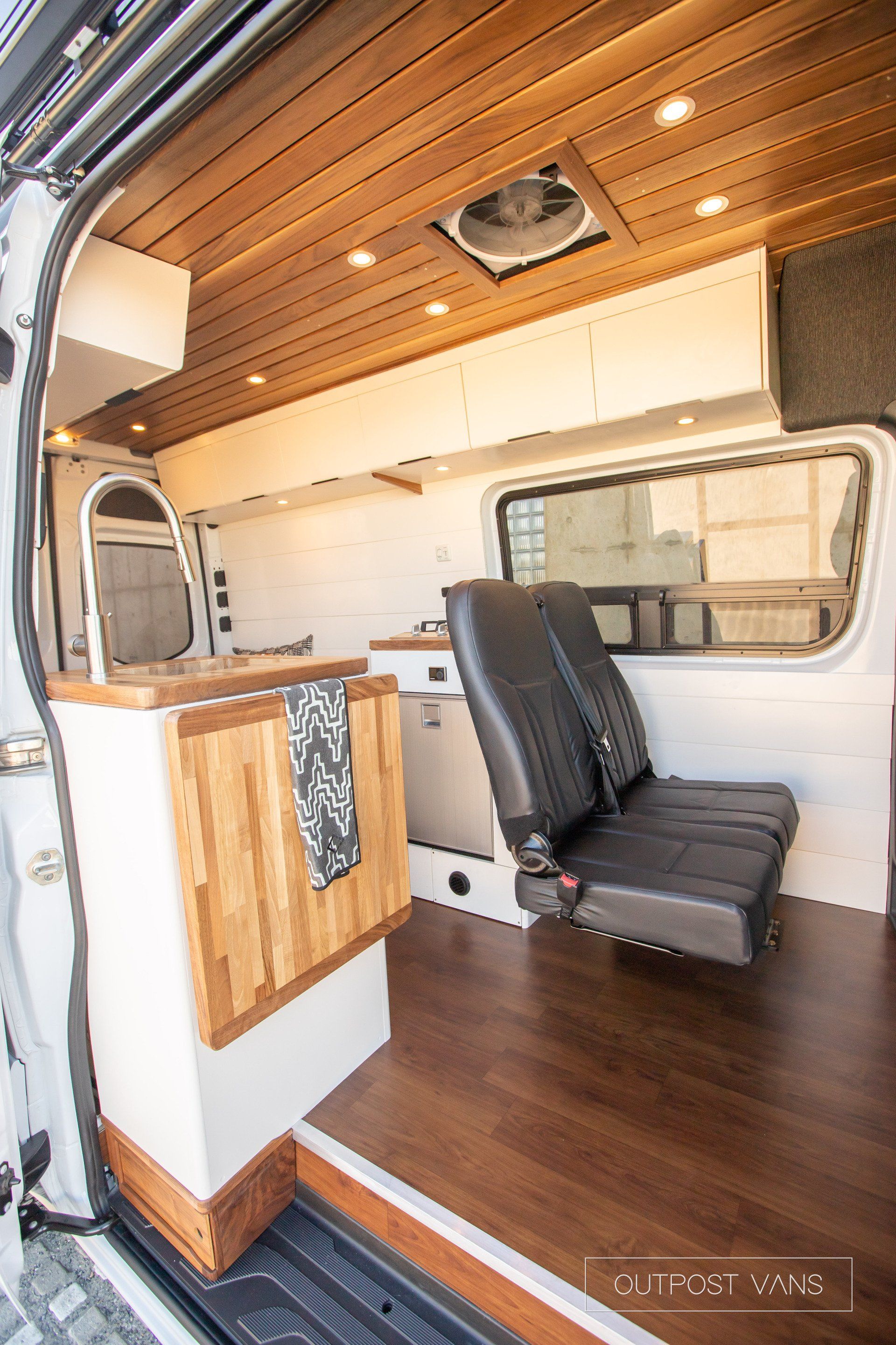 The inside of a van with a wooden floor and a black seat.