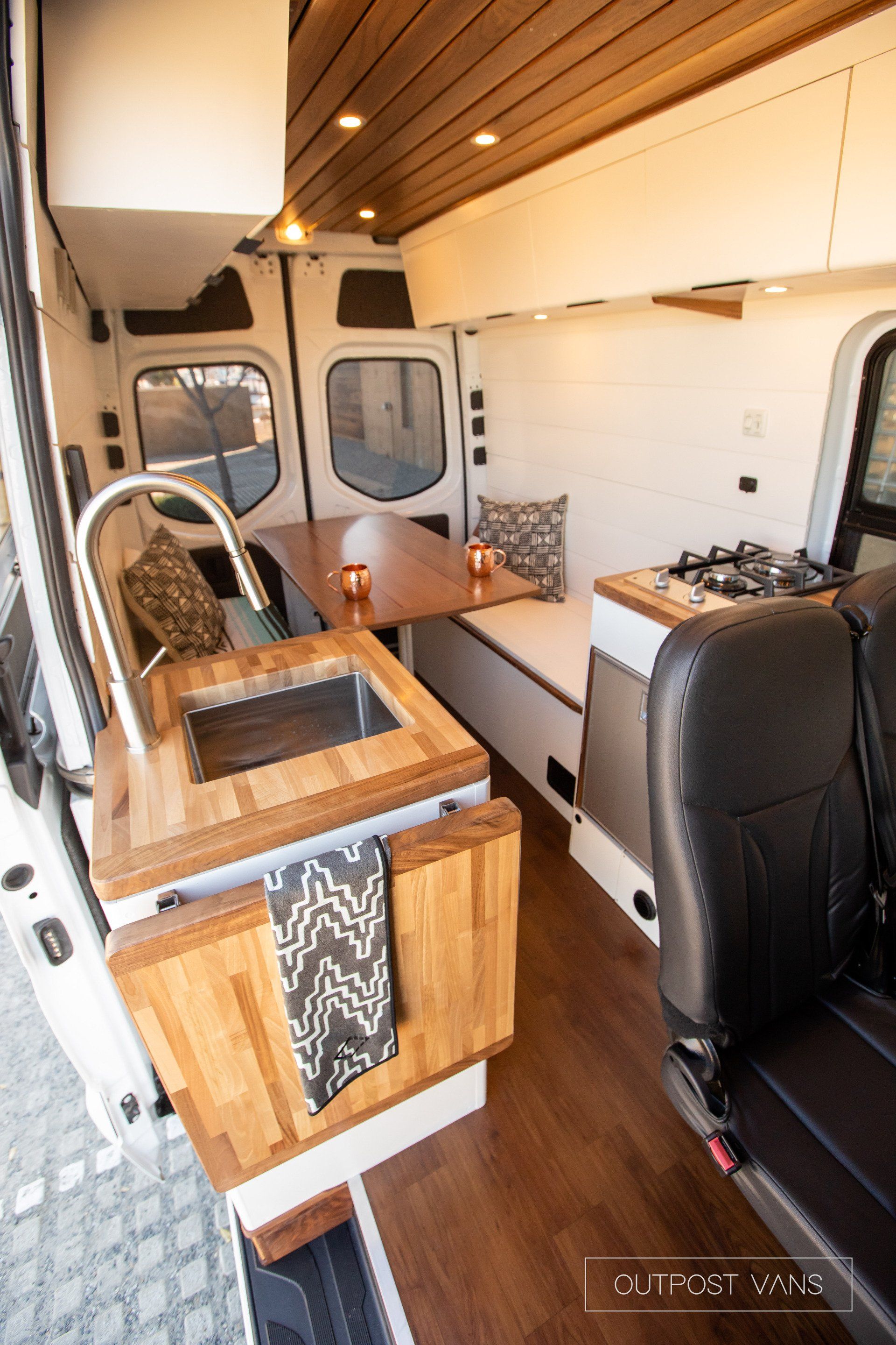 The inside of a van with a sink , table and chairs.