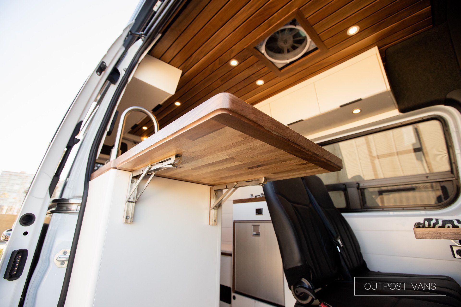 A van with a wooden table and a fan on the ceiling.