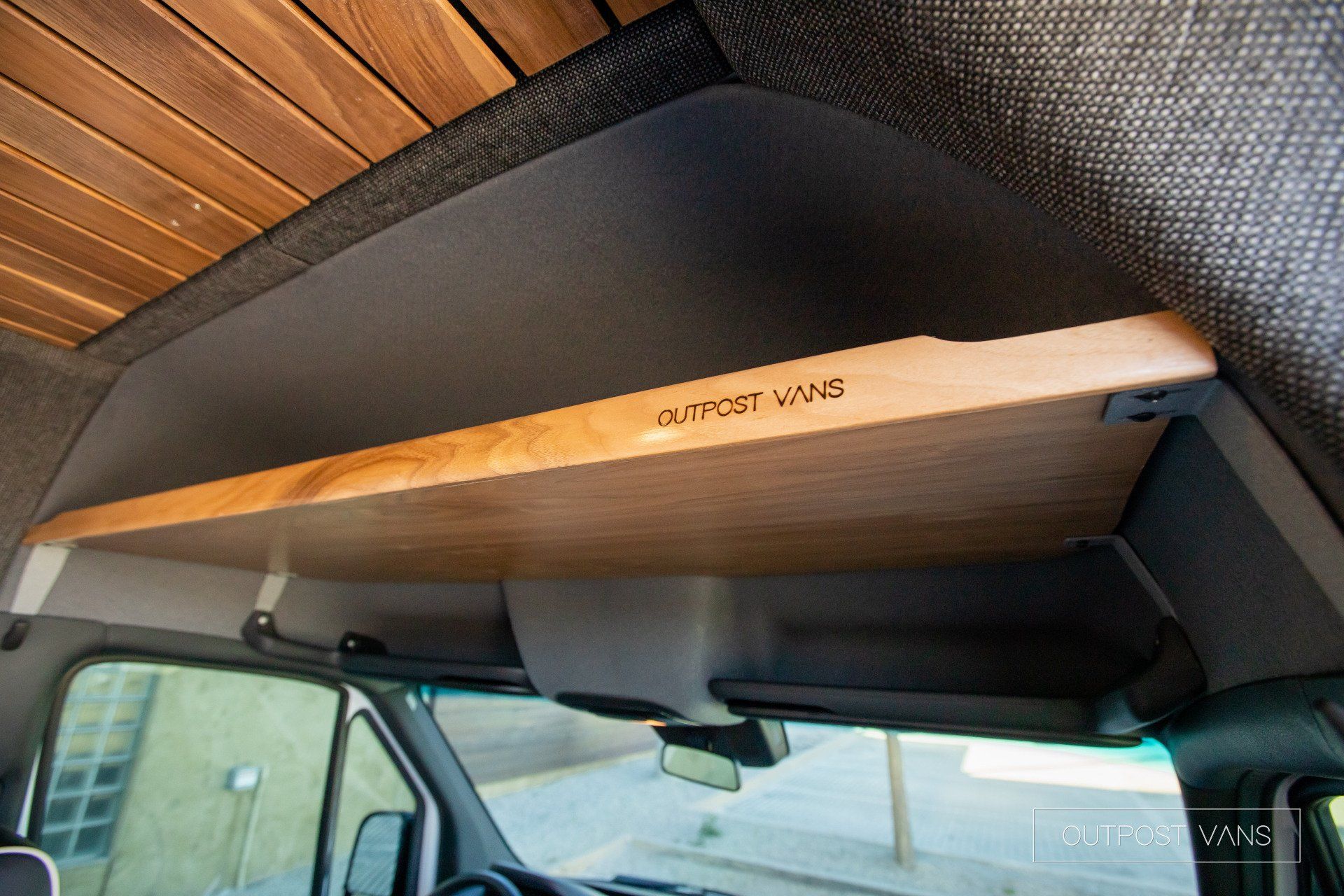A wooden shelf is hanging from the ceiling of a van.