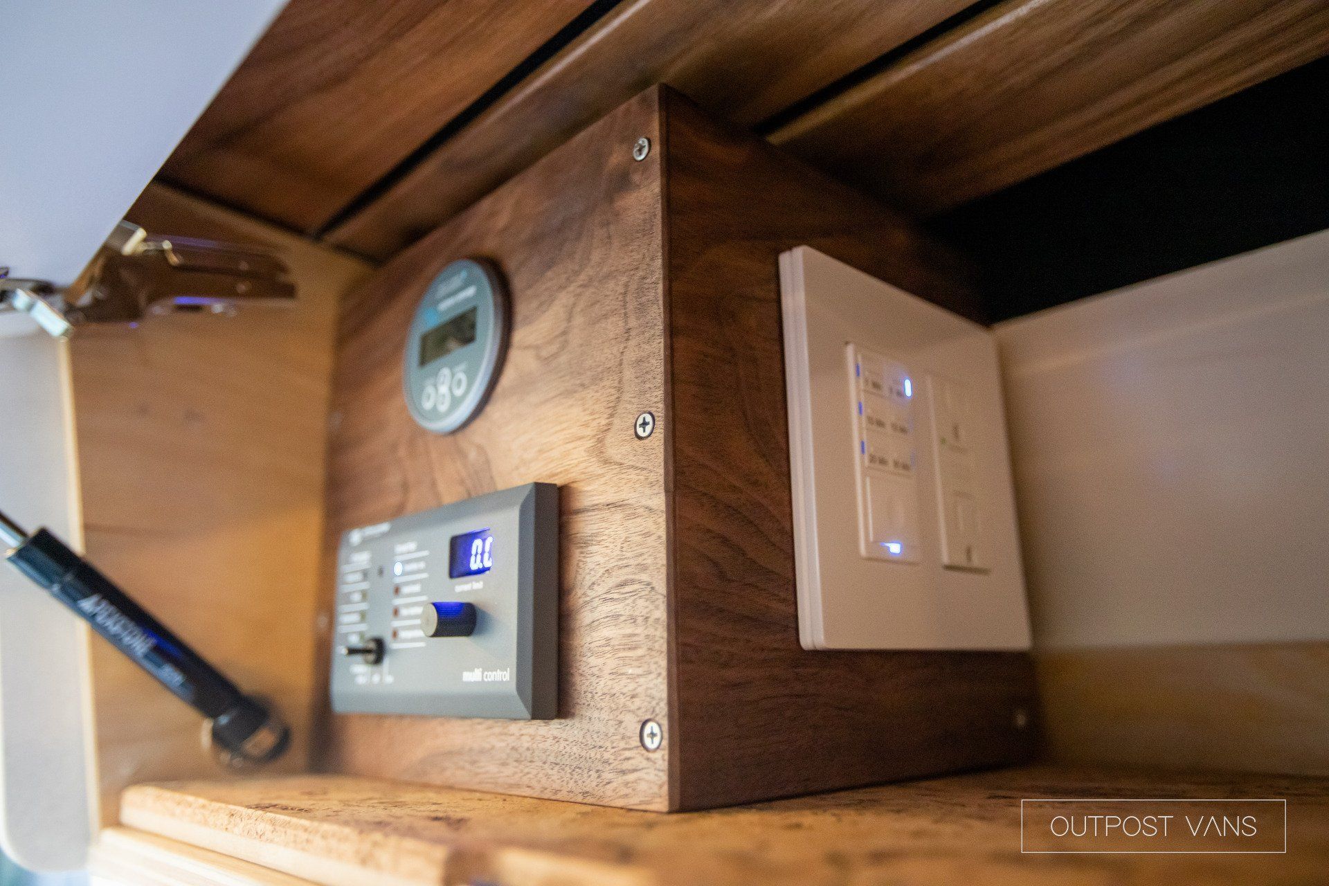 A wooden box sitting on top of a wooden shelf next to two electrical outlets.