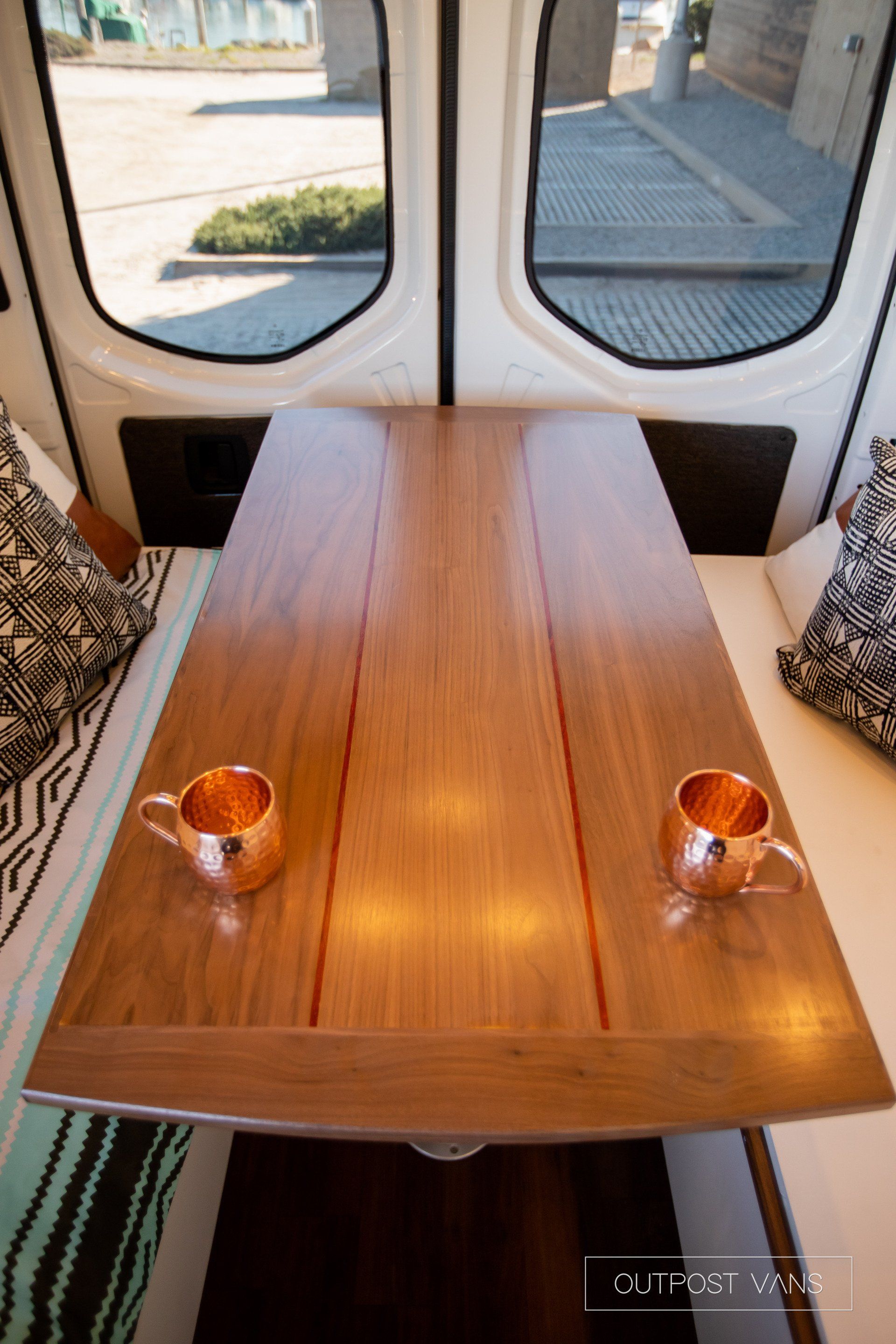 A wooden table with two cups on it in a van.