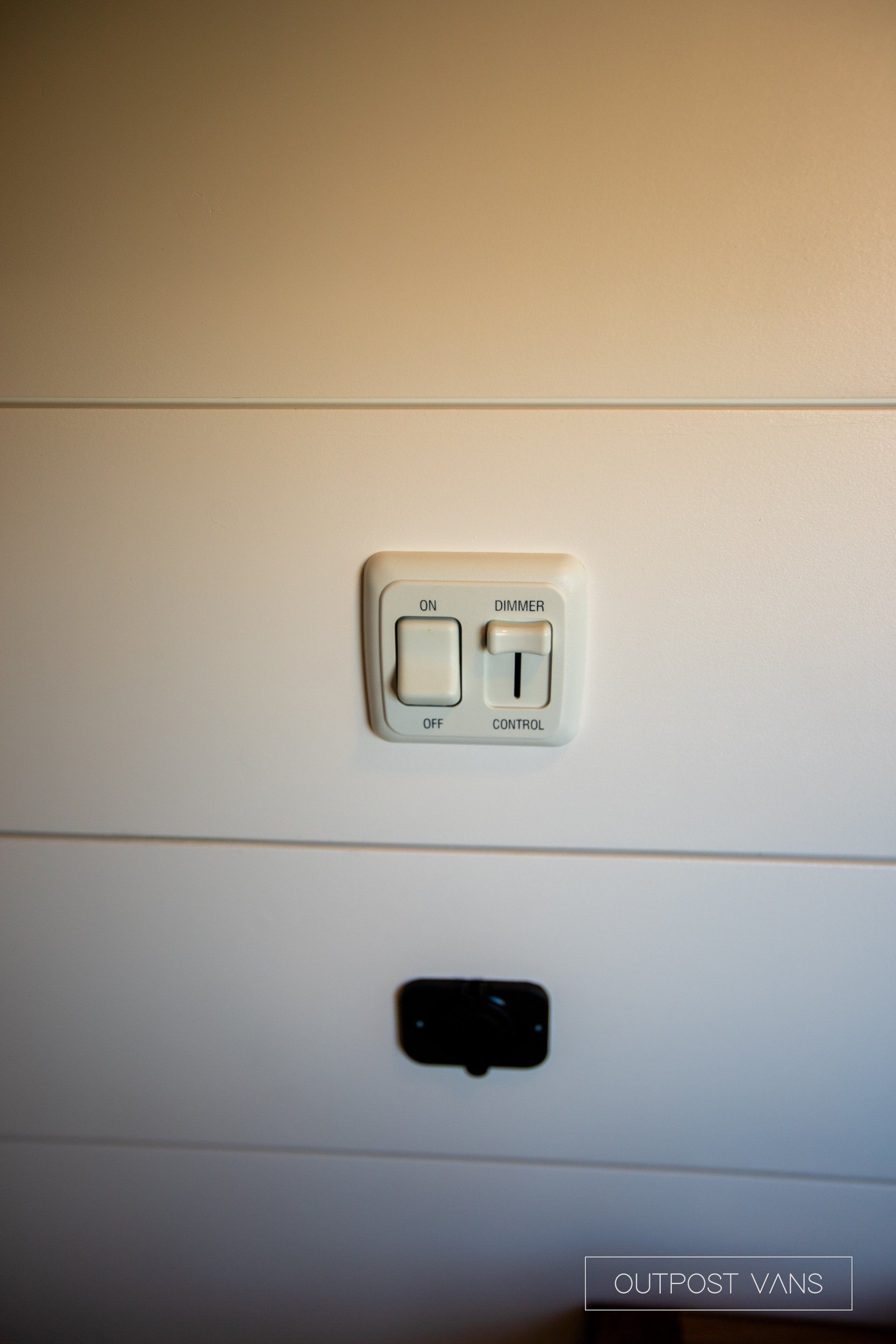 A close up of a light switch on a white wall.