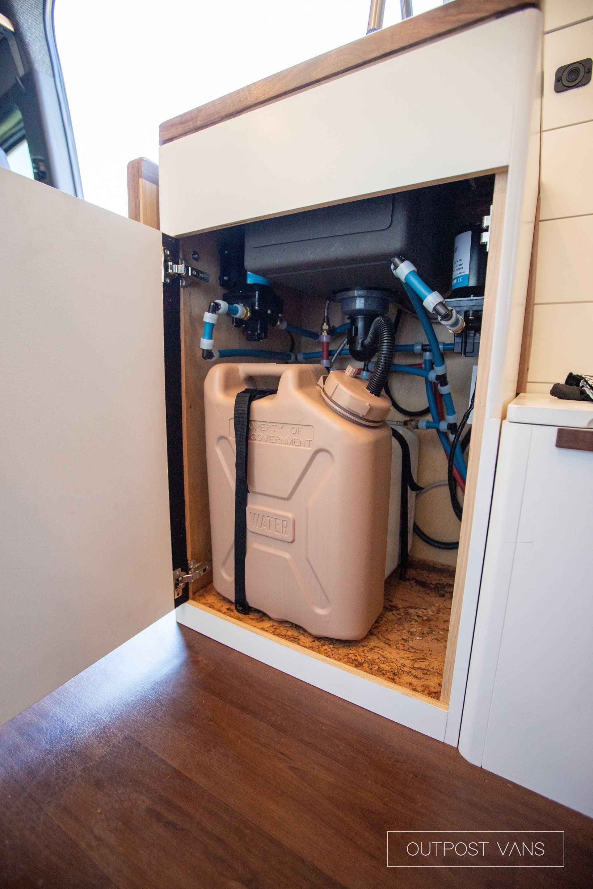 A plastic container is sitting under a sink in a kitchen.