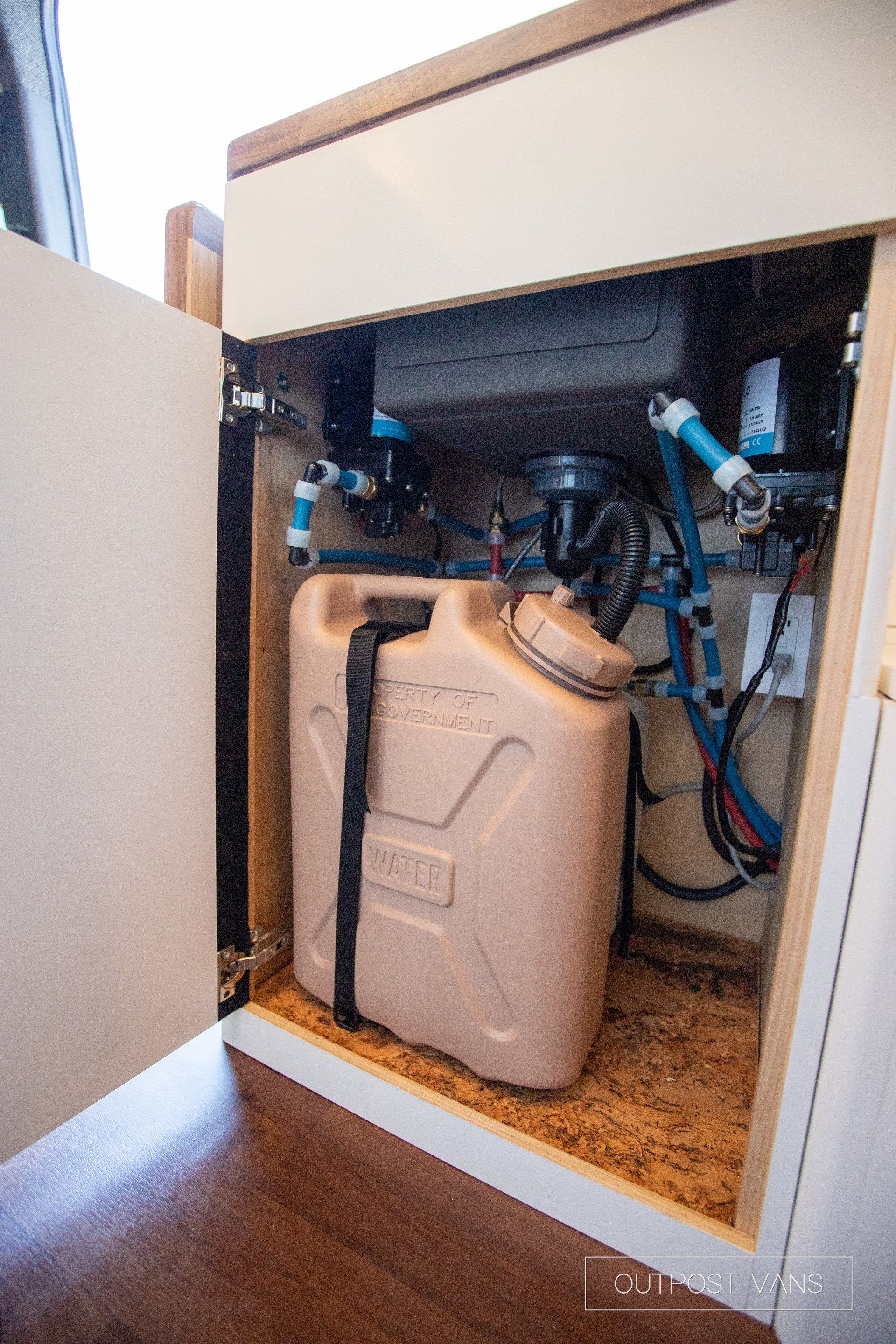 A jerry can is sitting under a sink in a cabinet.