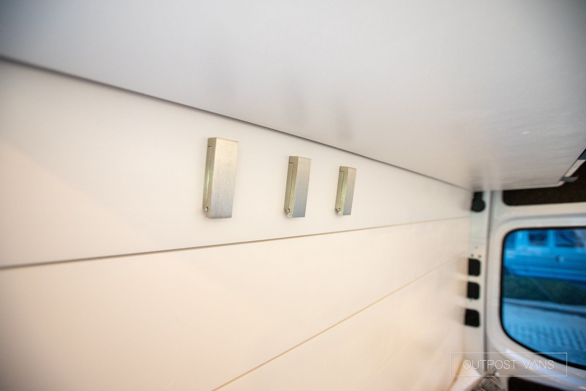 There are three hooks on the wall of a van.