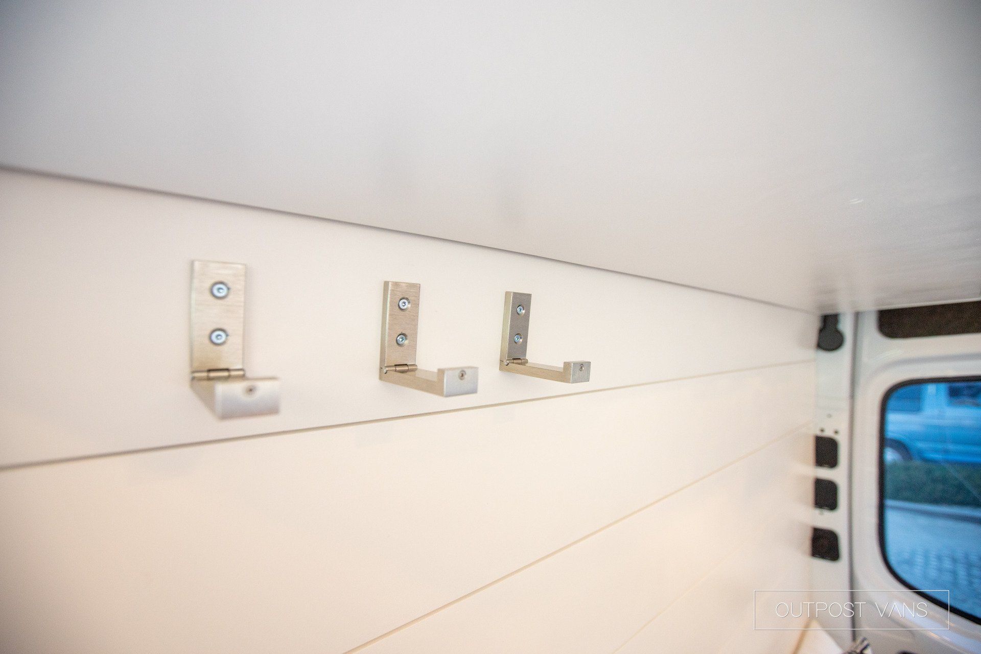 Three hooks are hanging on a wall in a van.