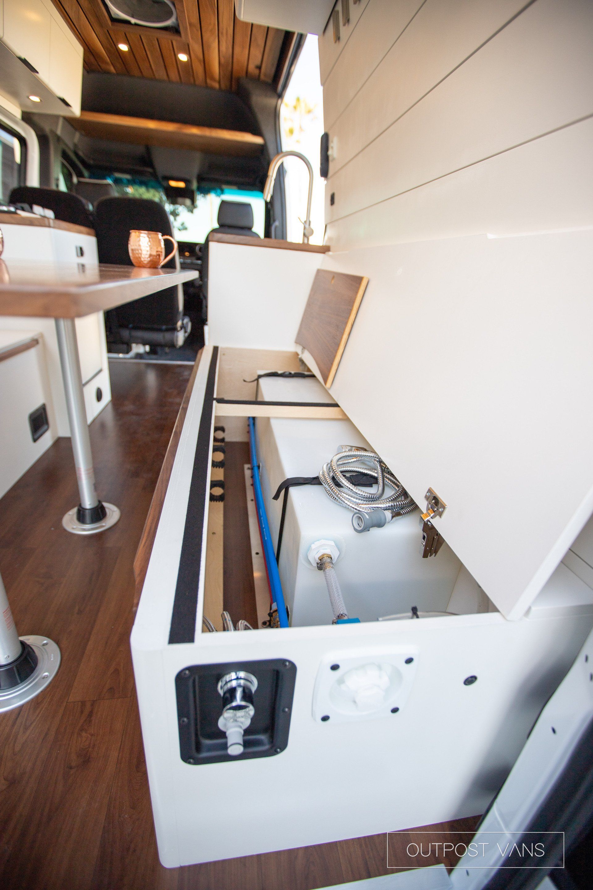 A van with a table and a water tank in the back.