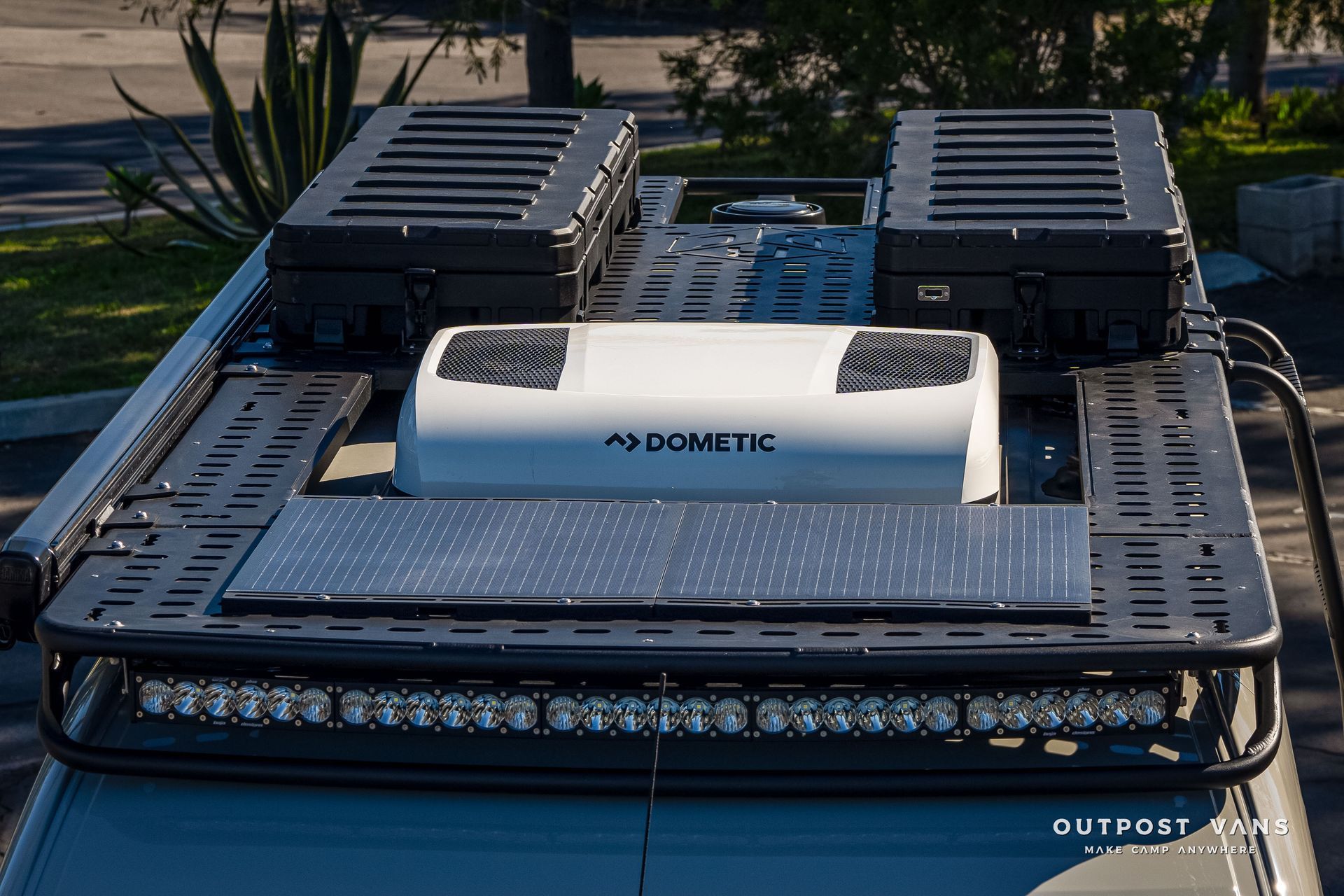 Van roof with black rack, solar panel, air conditioner, LED light bar, and storage boxes.