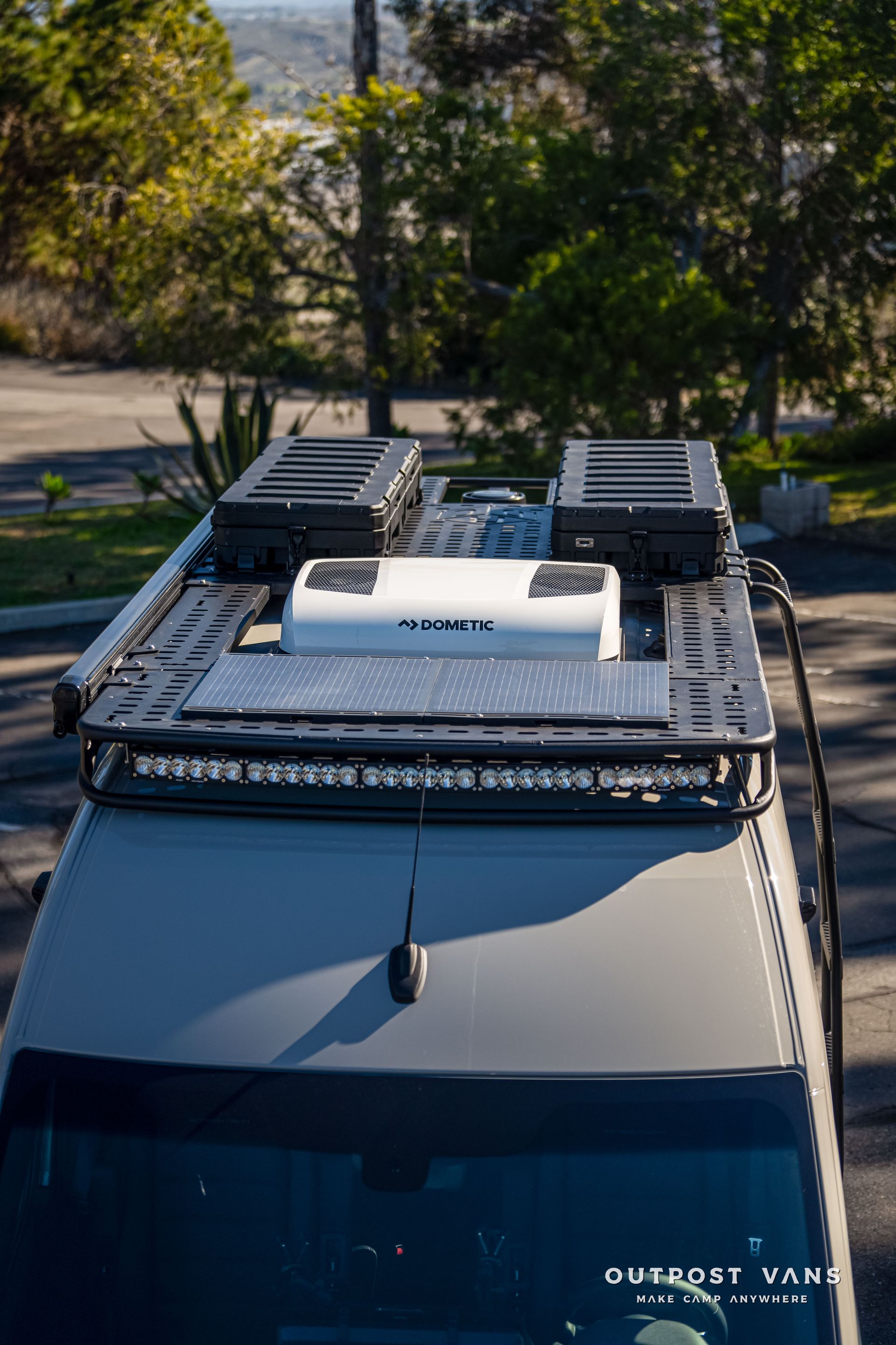 Van roof with solar panel, storage boxes, light bar, and AC unit.