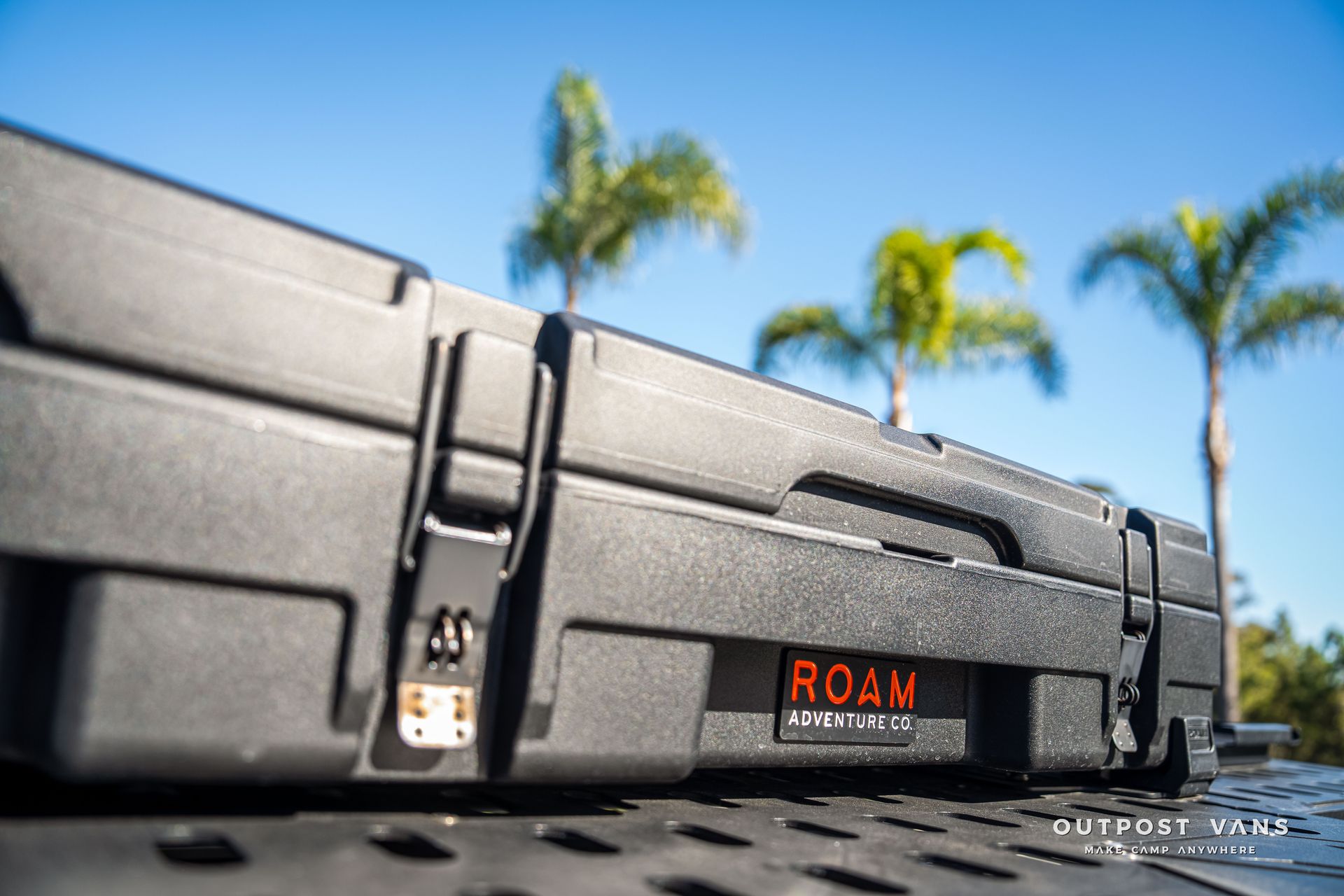 Black ROAM Adventure gear case, orange logo, palm trees in the background.