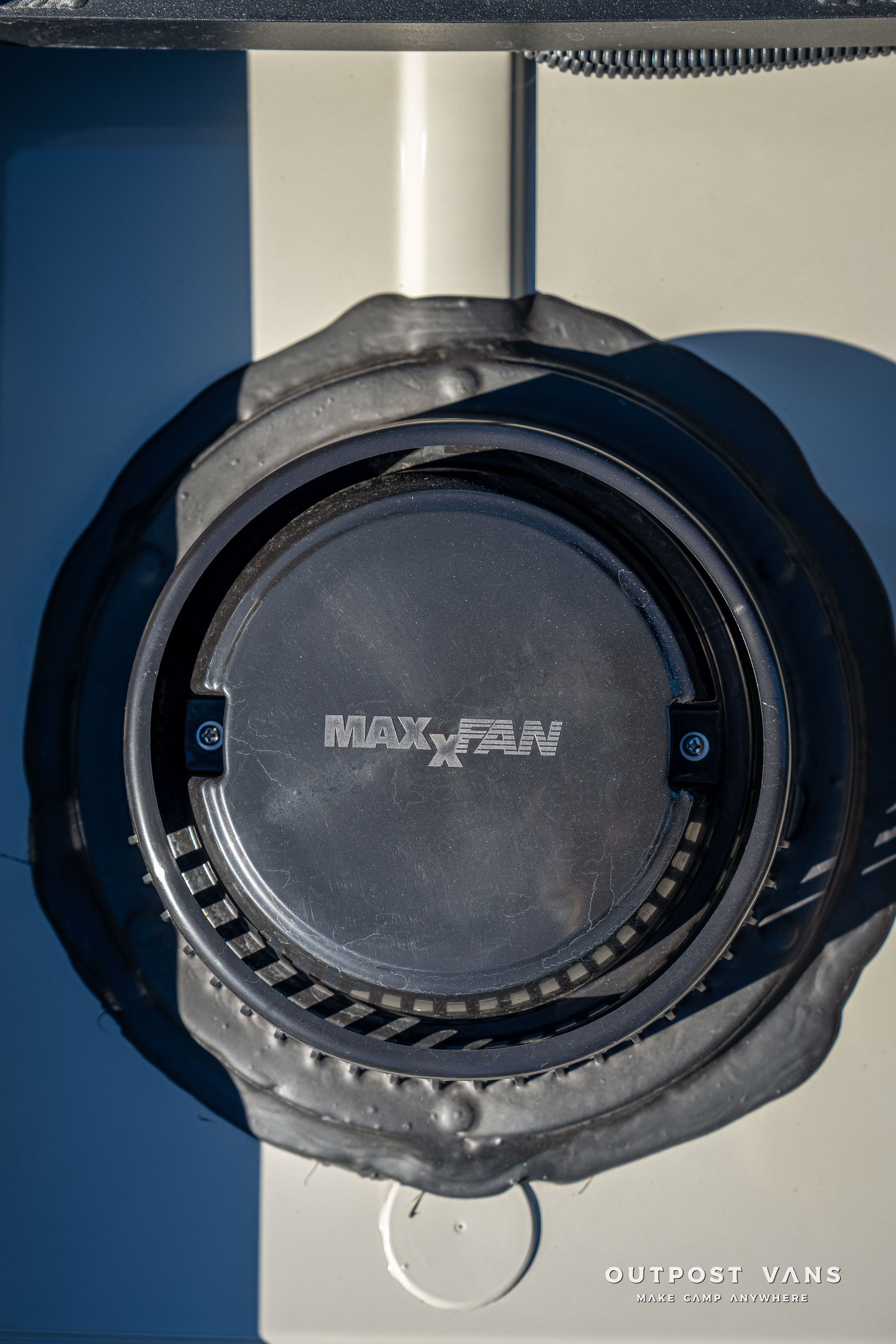 Close-up view of a black MAX-FLOW air vent set in a white vehicle body with a white stripe.