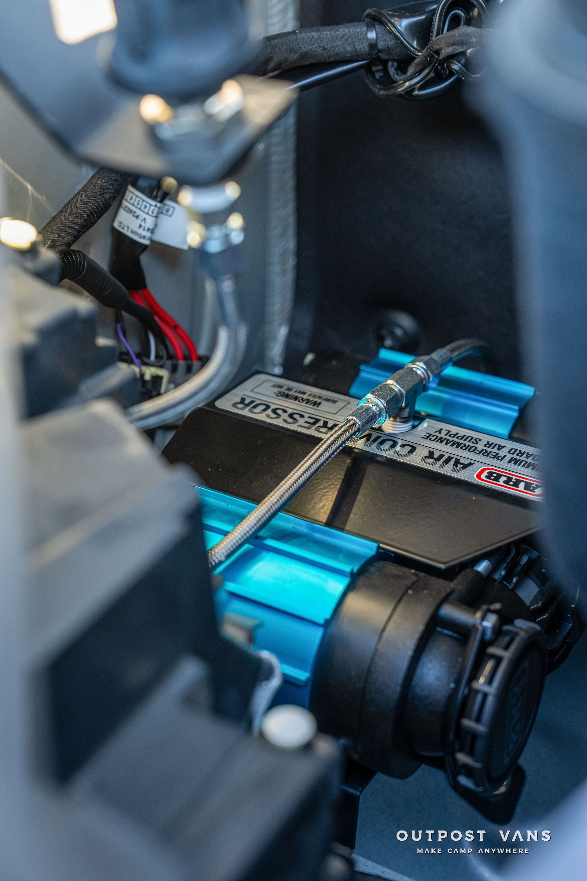 Blue air compressor installed in a vehicle, with black and metal components.