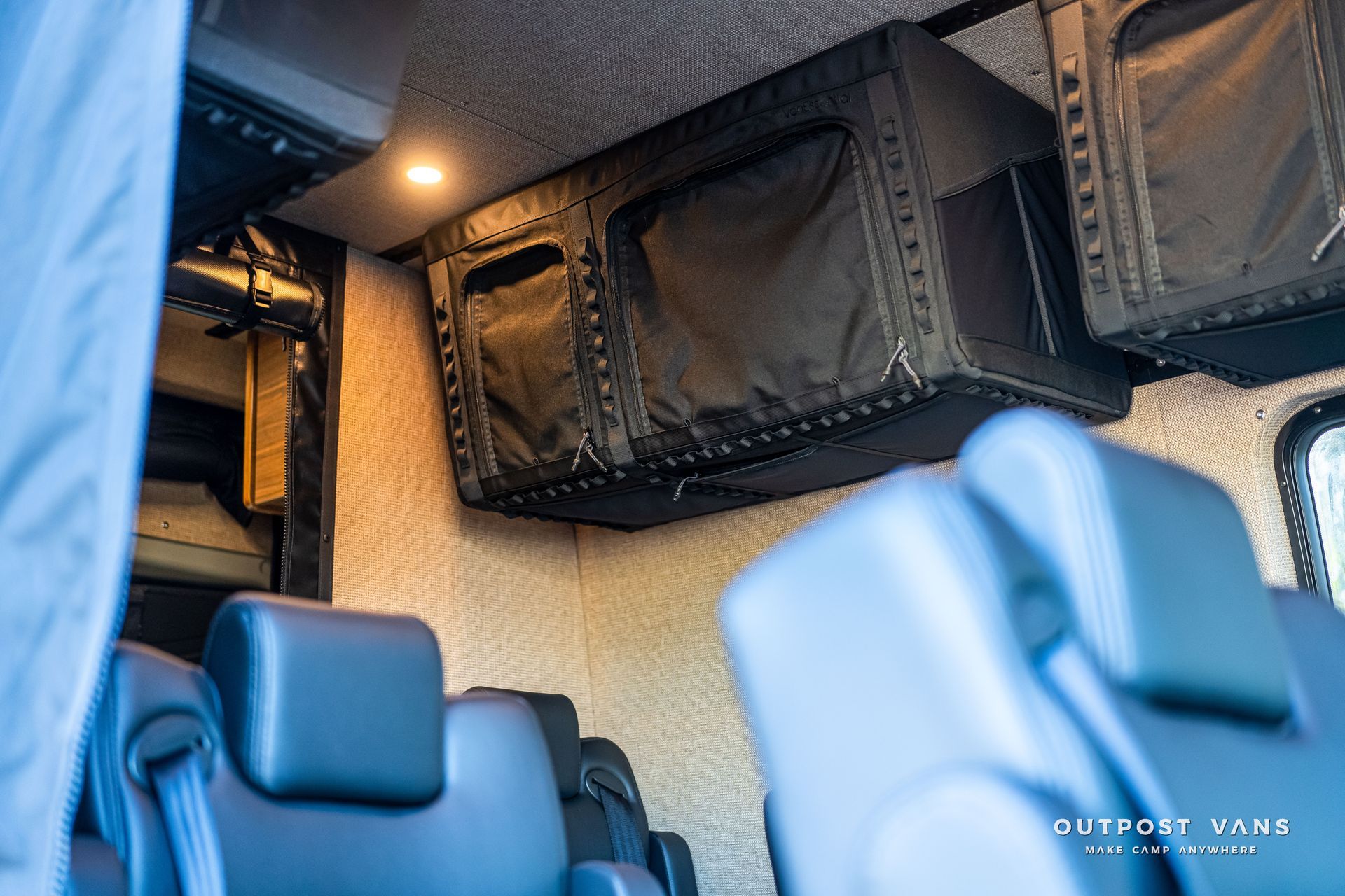 Interior of a van with overhead storage compartments and blue seats.