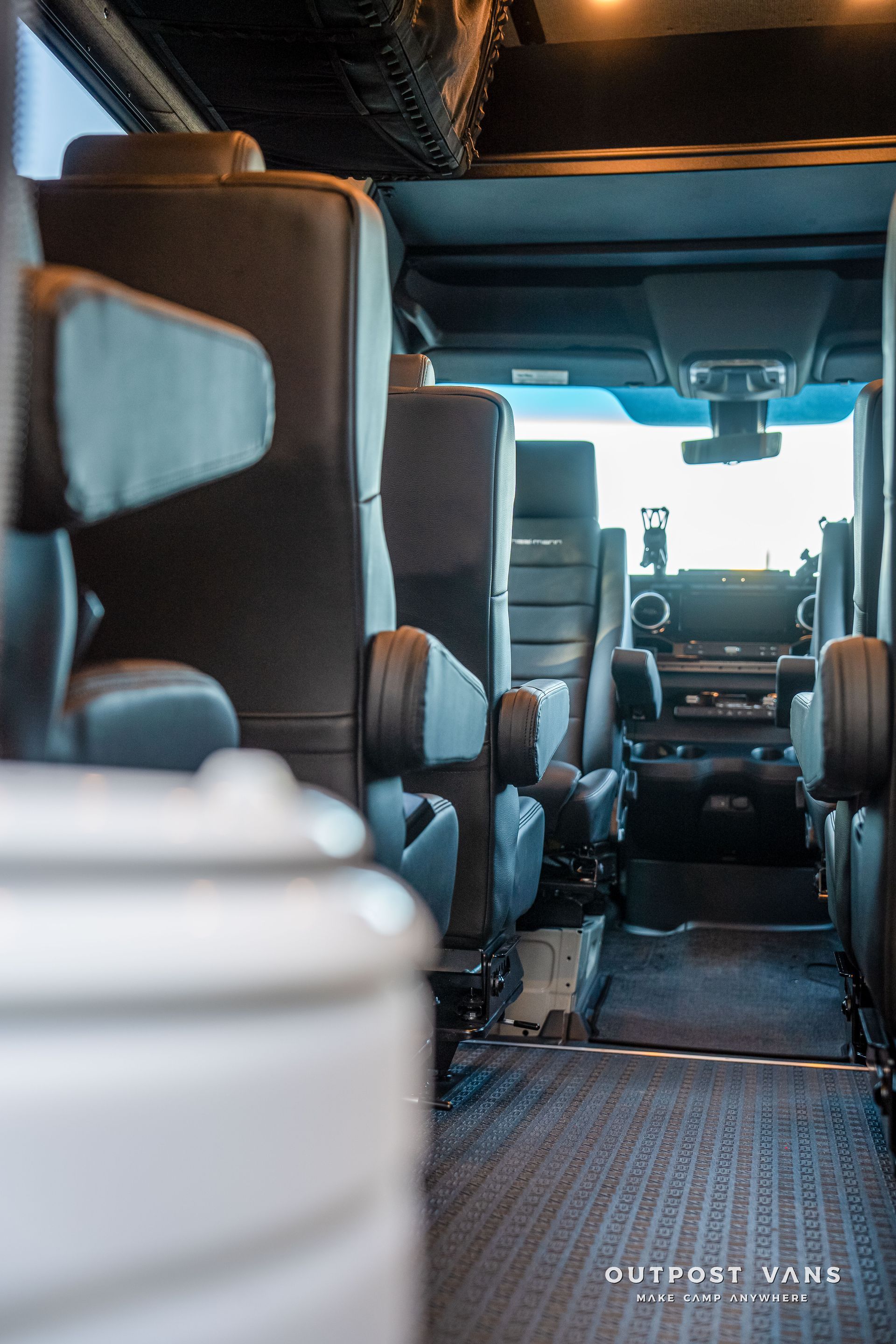 Interior view of a vehicle with rows of black seats and a dashboard visible in the distance.