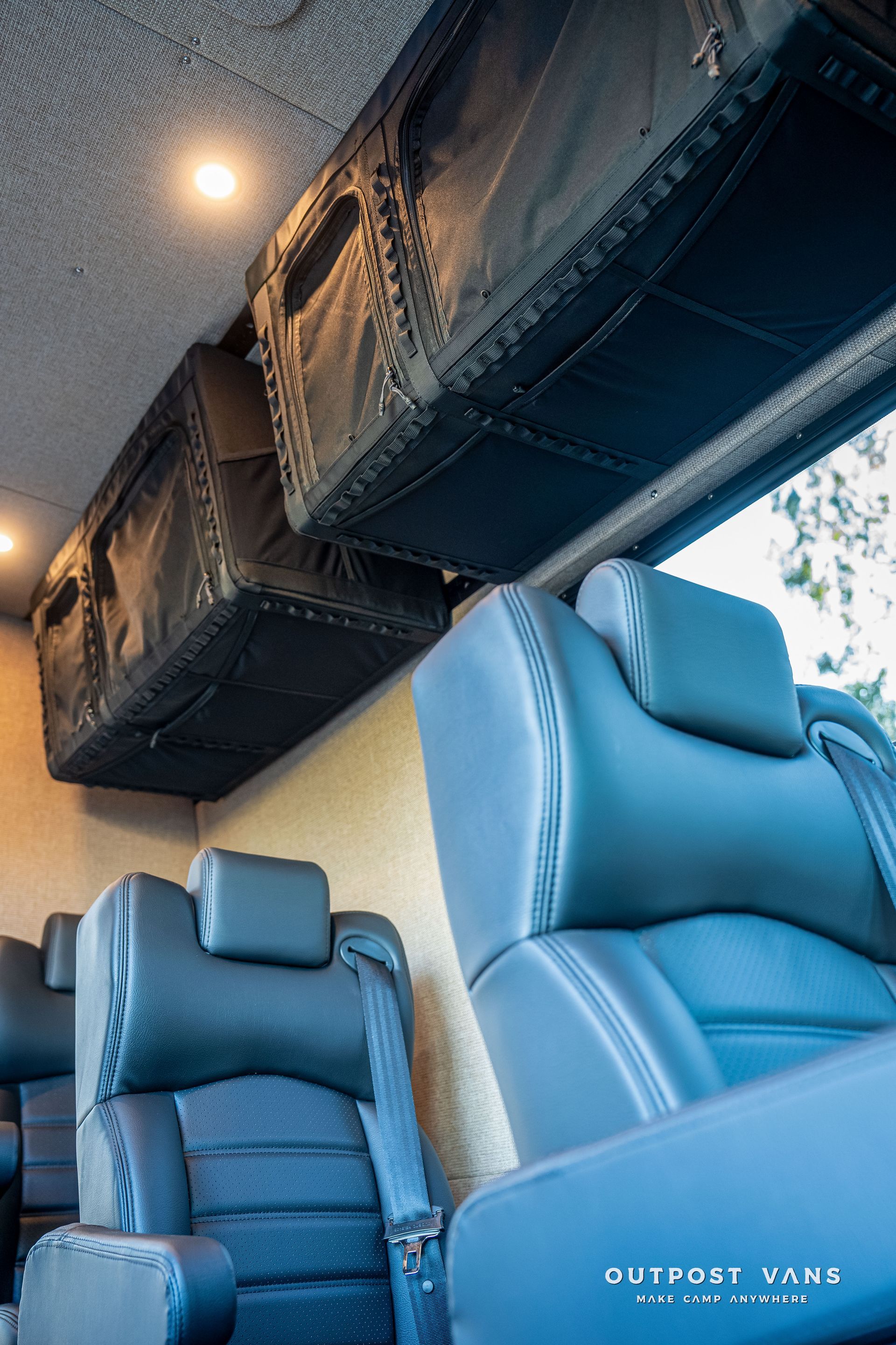Interior of a van with black leather seats and overhead storage compartments.