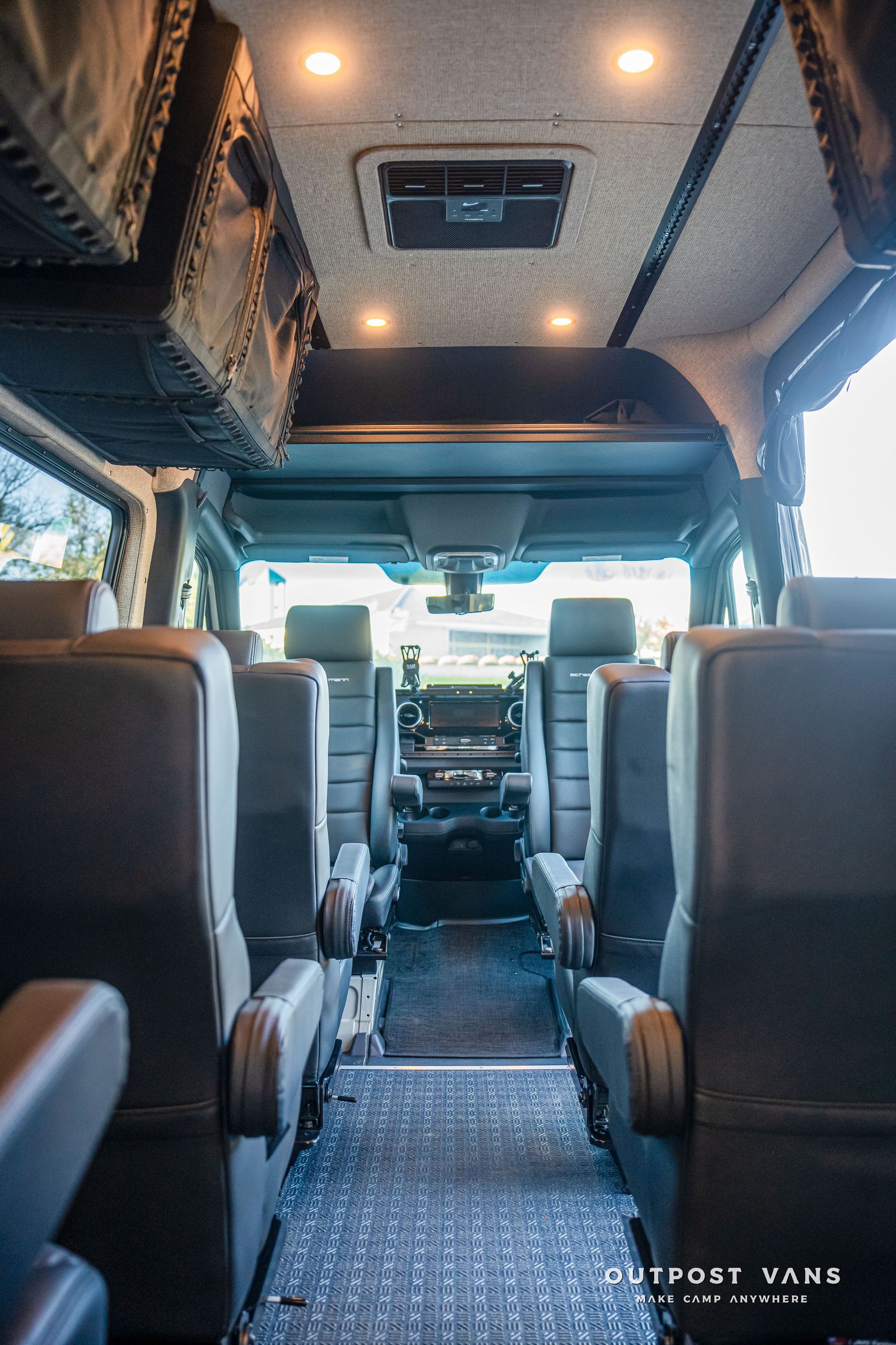 Interior of a van with dark gray seats and overhead storage, looking towards the driver's area.