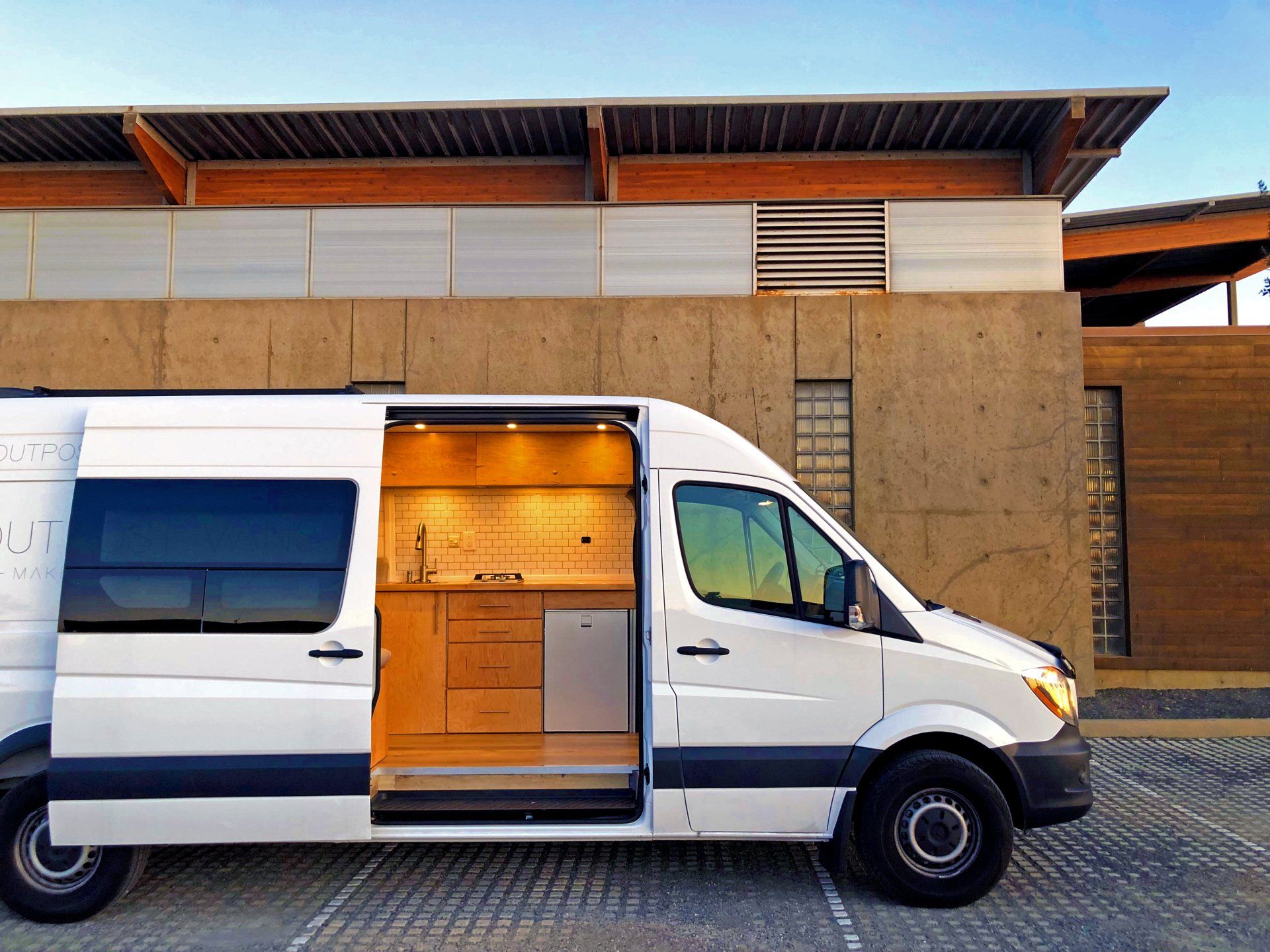 a white van with the door open is parked in front of a building